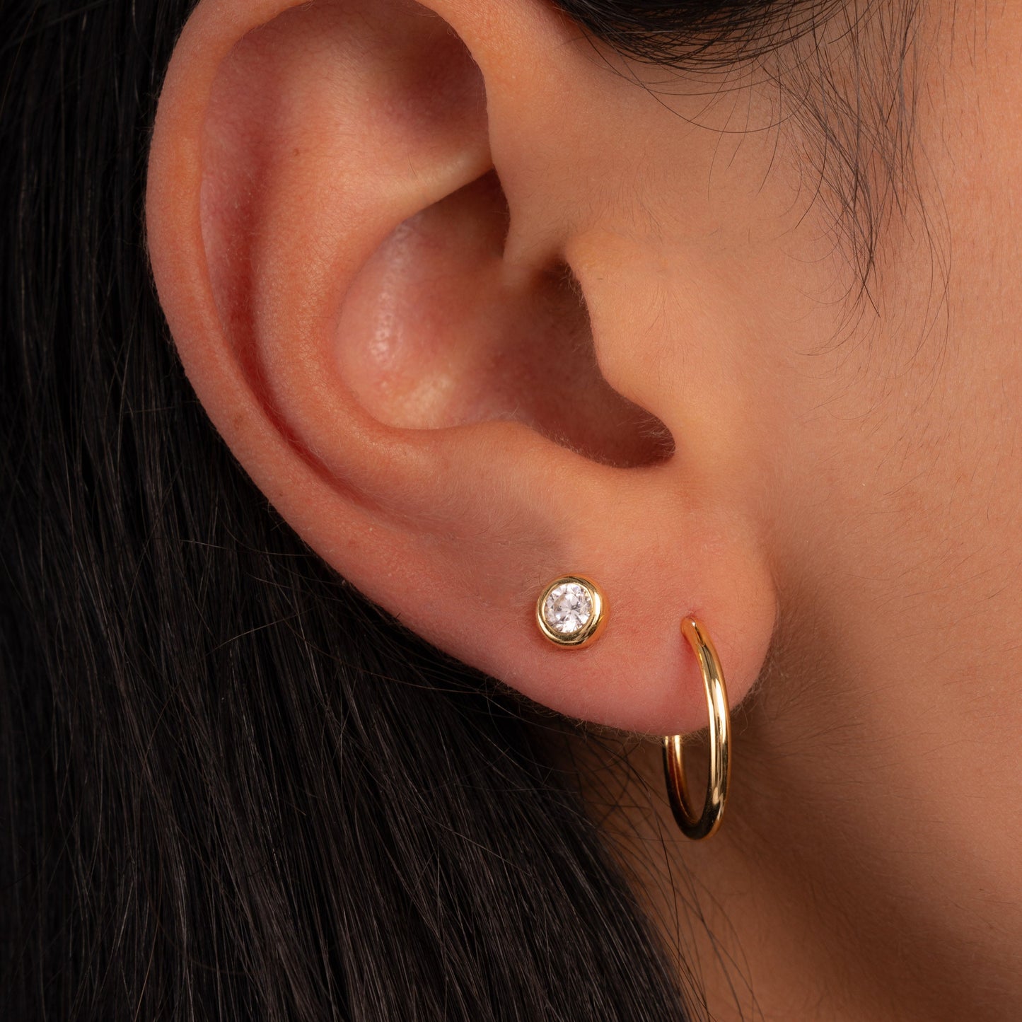 thin mini gold hoop earring on model paired with stud earring
