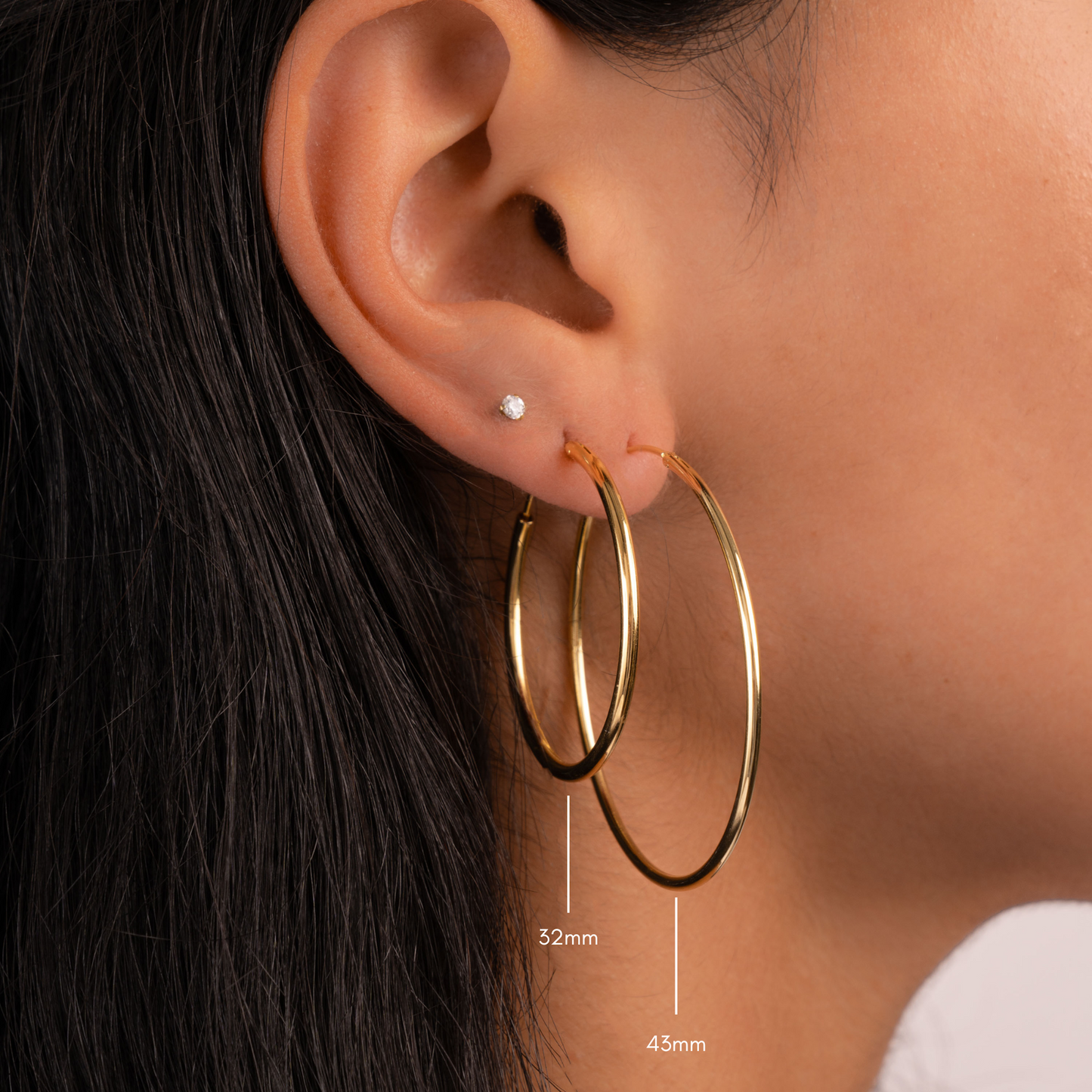 Model wearing one large gold hoop and one medium sizes gold hoop