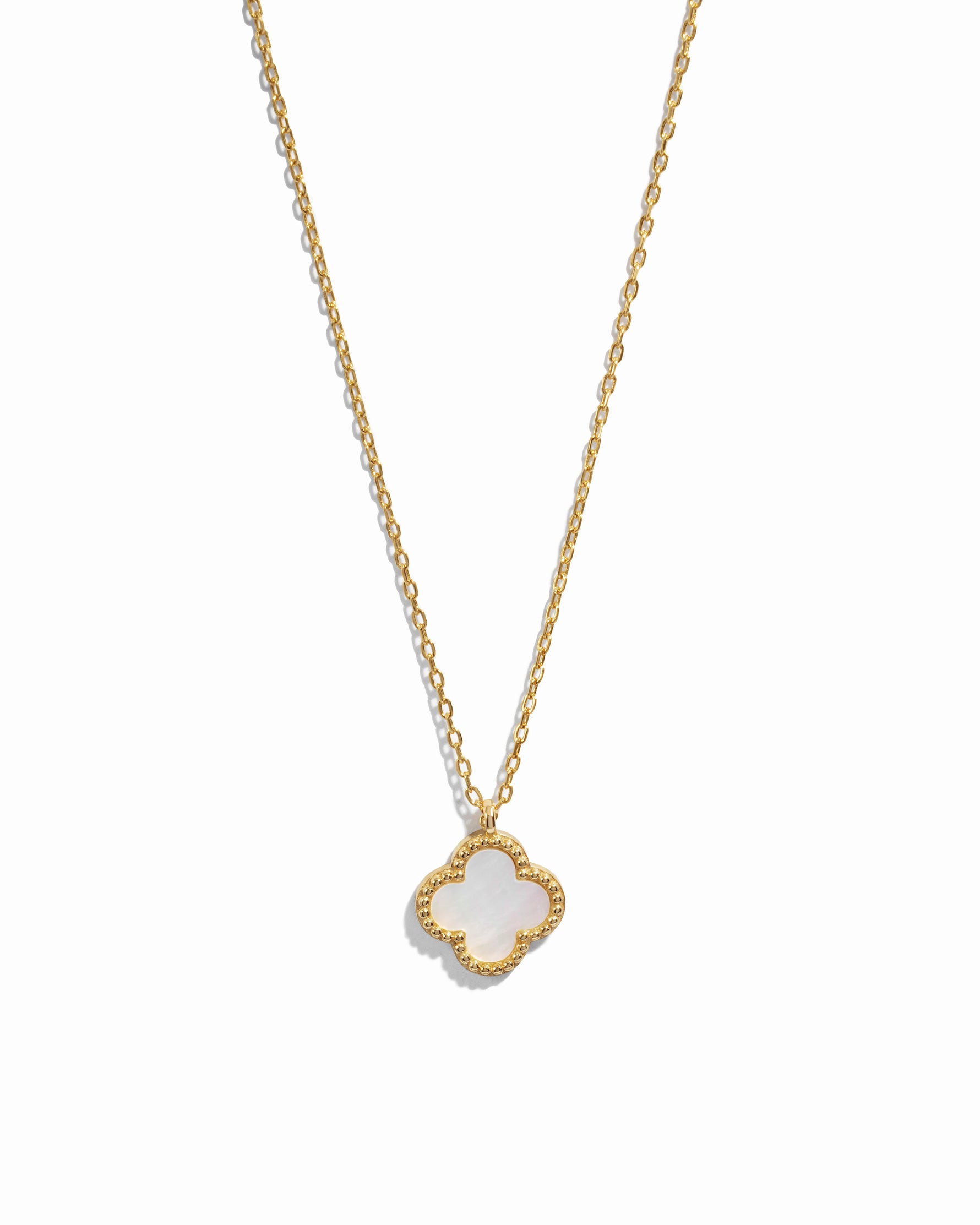 Gold necklace with a clover-shaped pendant set with mother of pearl on a white background