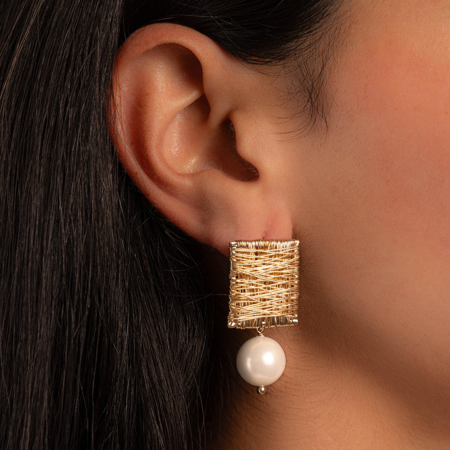 model wearing statement earrings featuring square earrings with a freshwater pearl charm