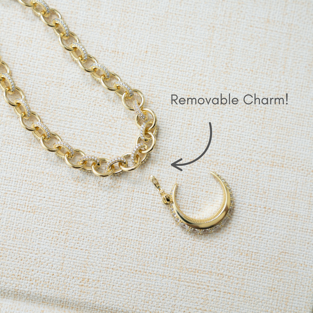 closeup image showcasing gold statement necklace with removable cubic zirconia moon charm