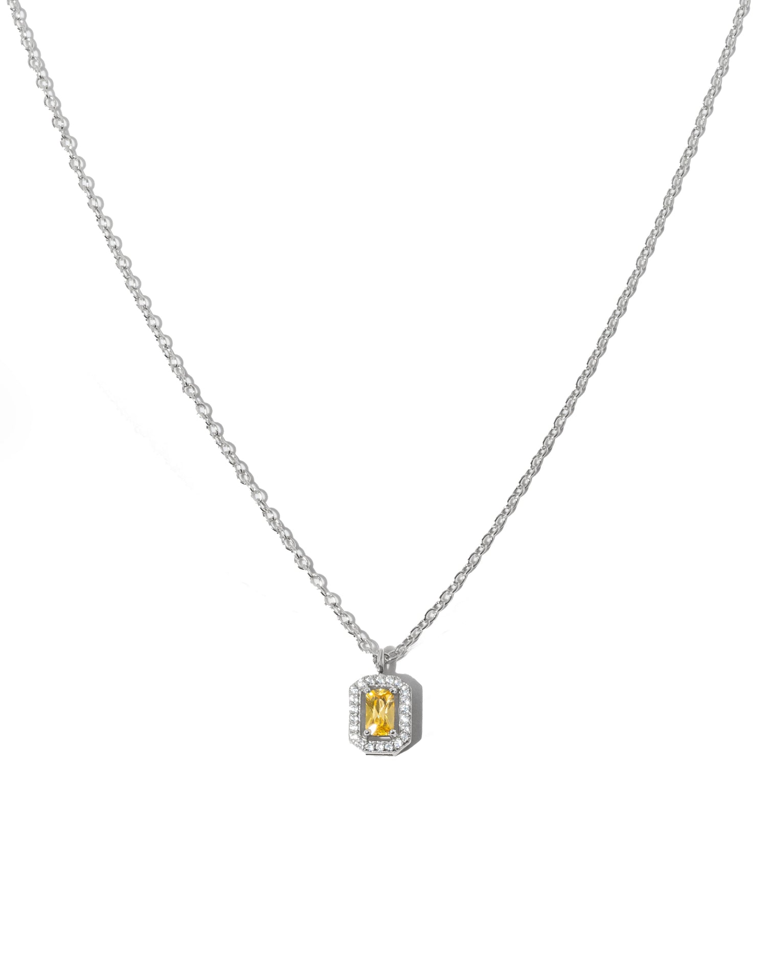 Silver chain necklace with a yellow gemstone pendant on a white background