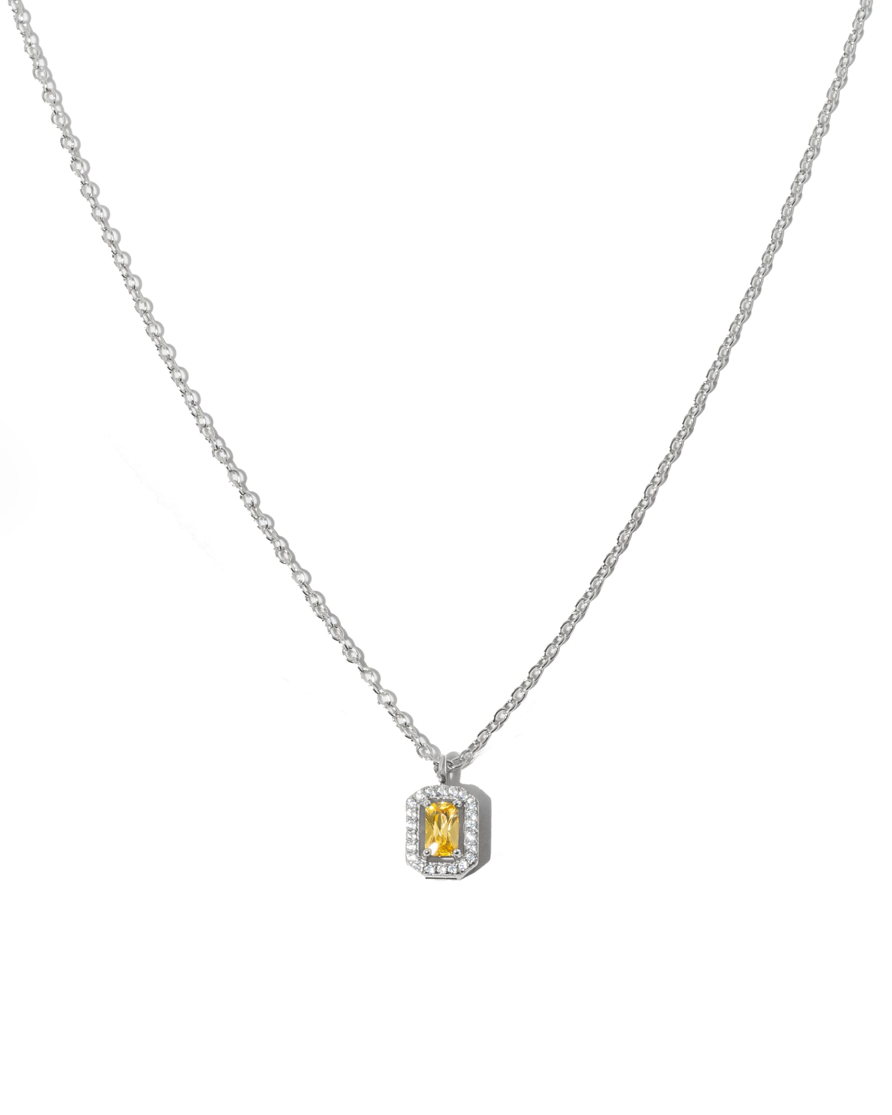Silver chain necklace with a yellow gemstone pendant on a white background