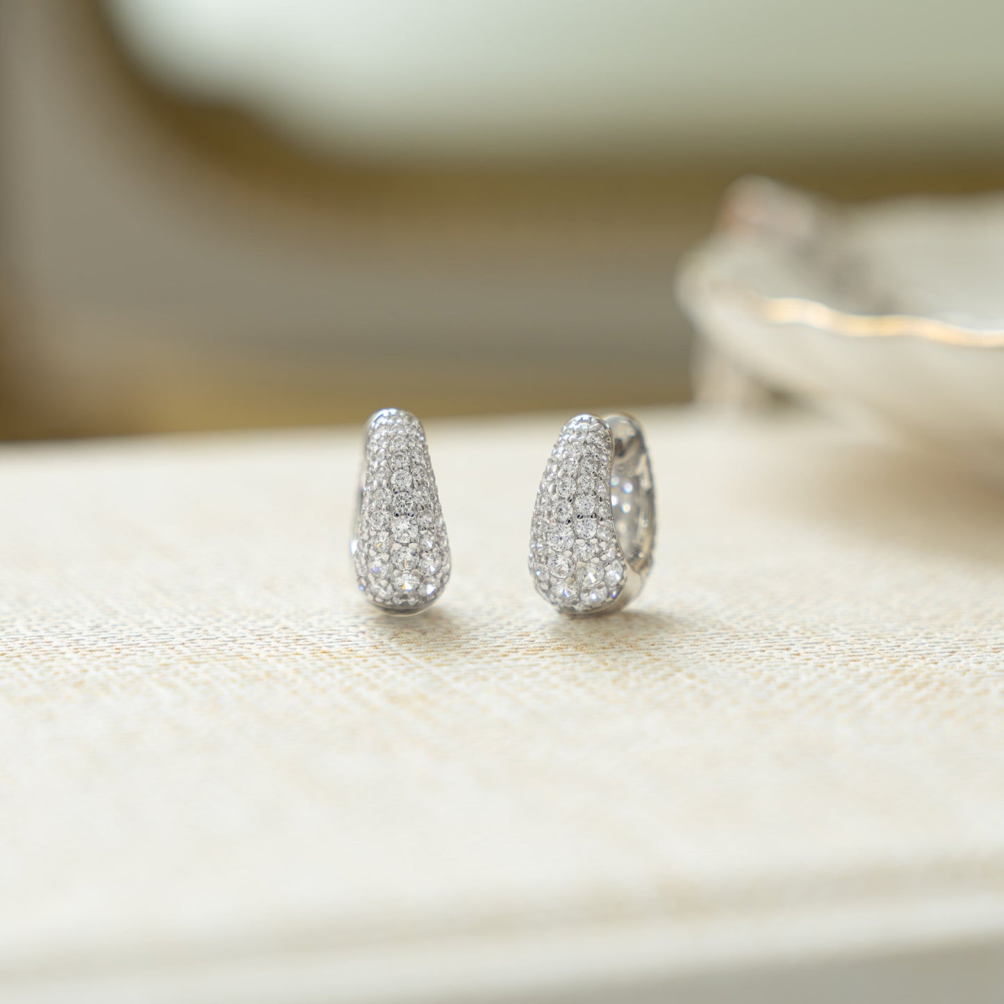 closeup image of small silver huggie hoops with cubic zirconia diamonds