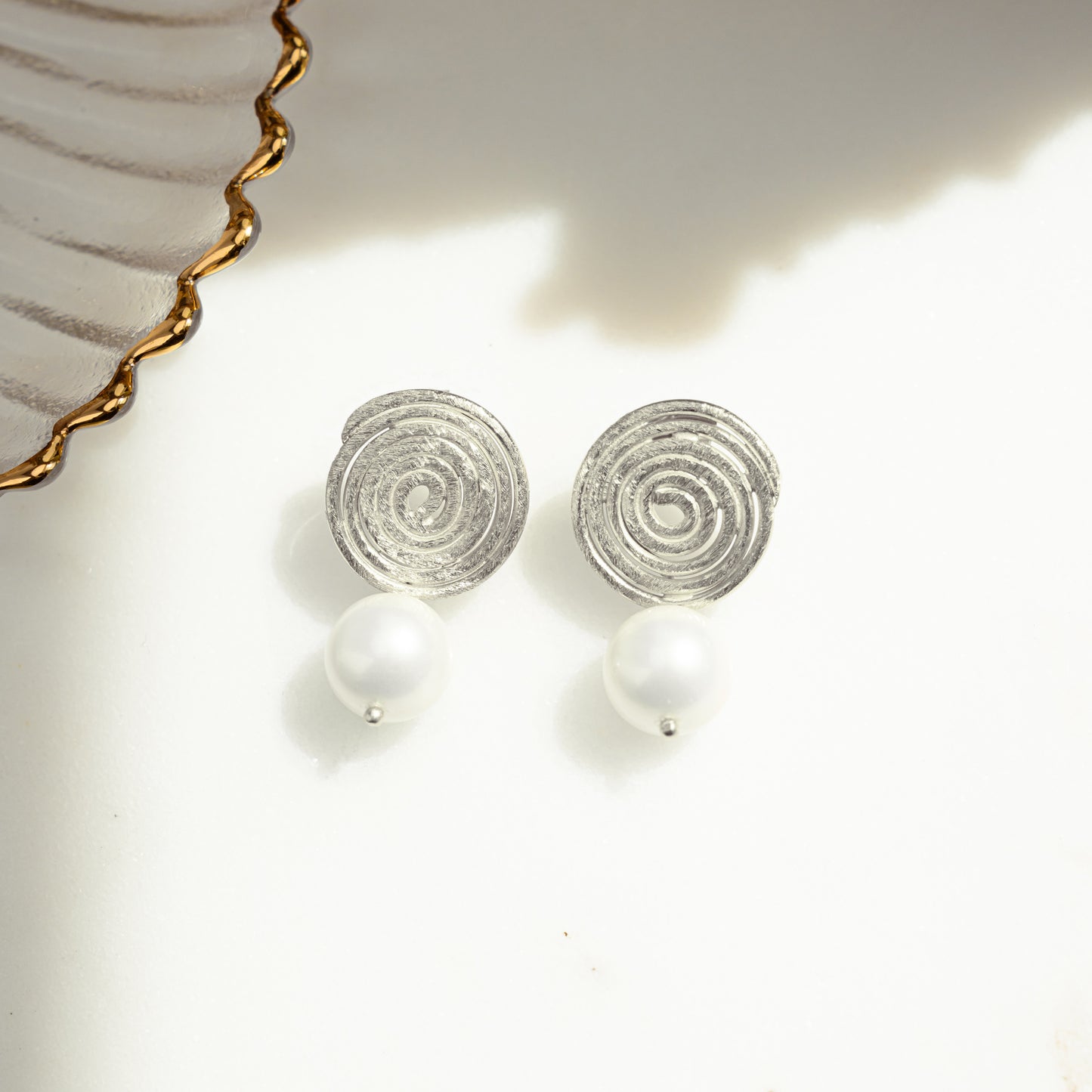 close-up image of silver spiral earrings with a dangle drop freshwater pearl