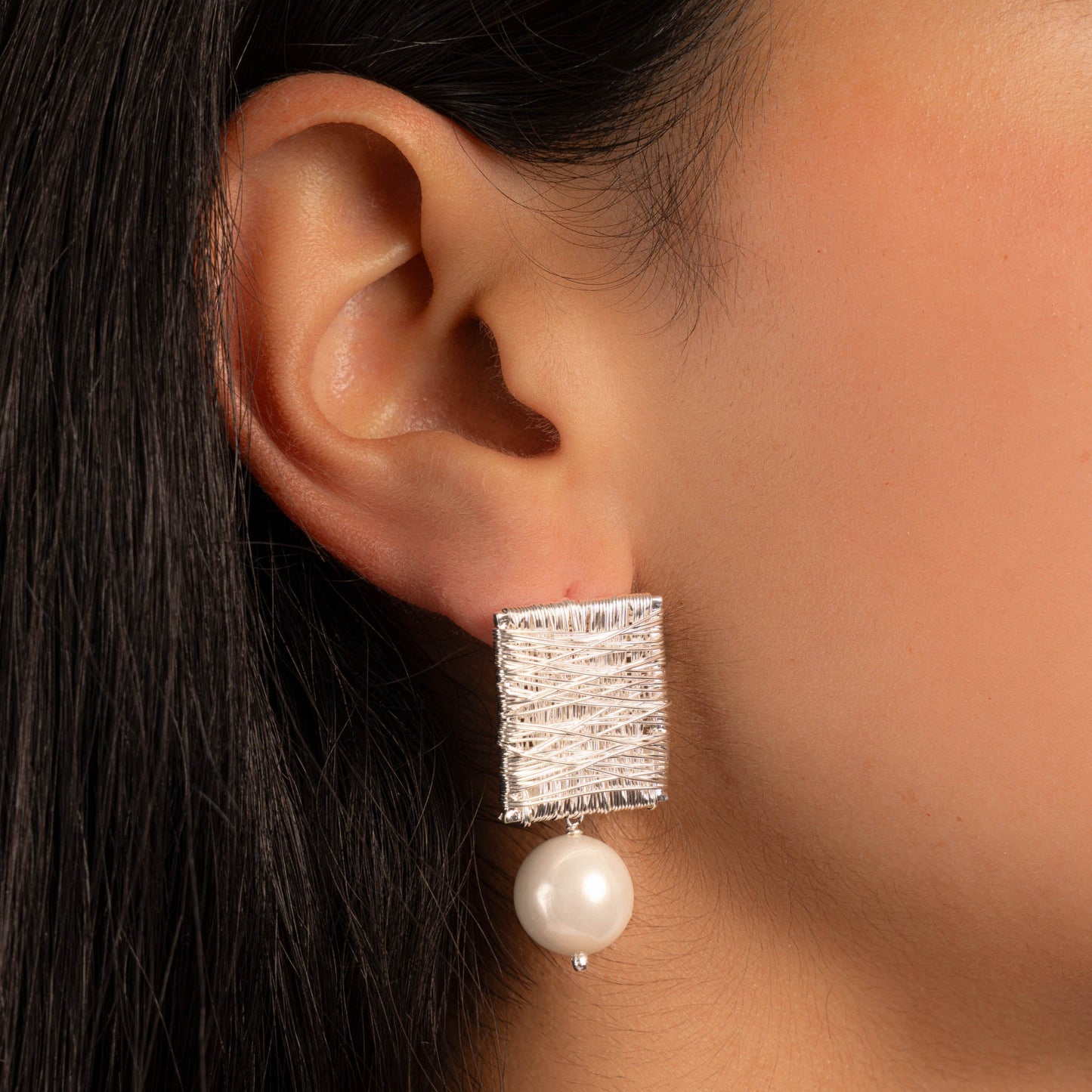 model wearing boho earrings featuring a square earring and pearl charm