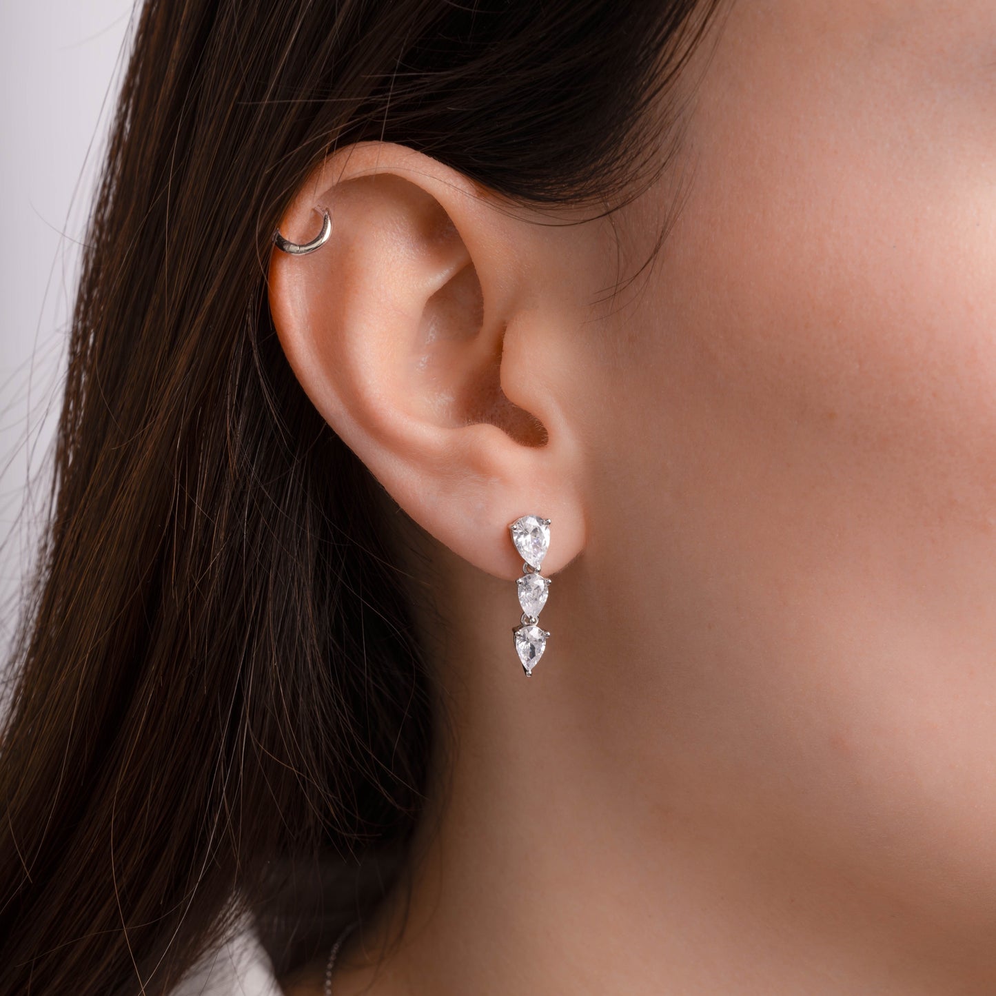 Model wearing drop earrings with a pear-cut gemstones set in silver.