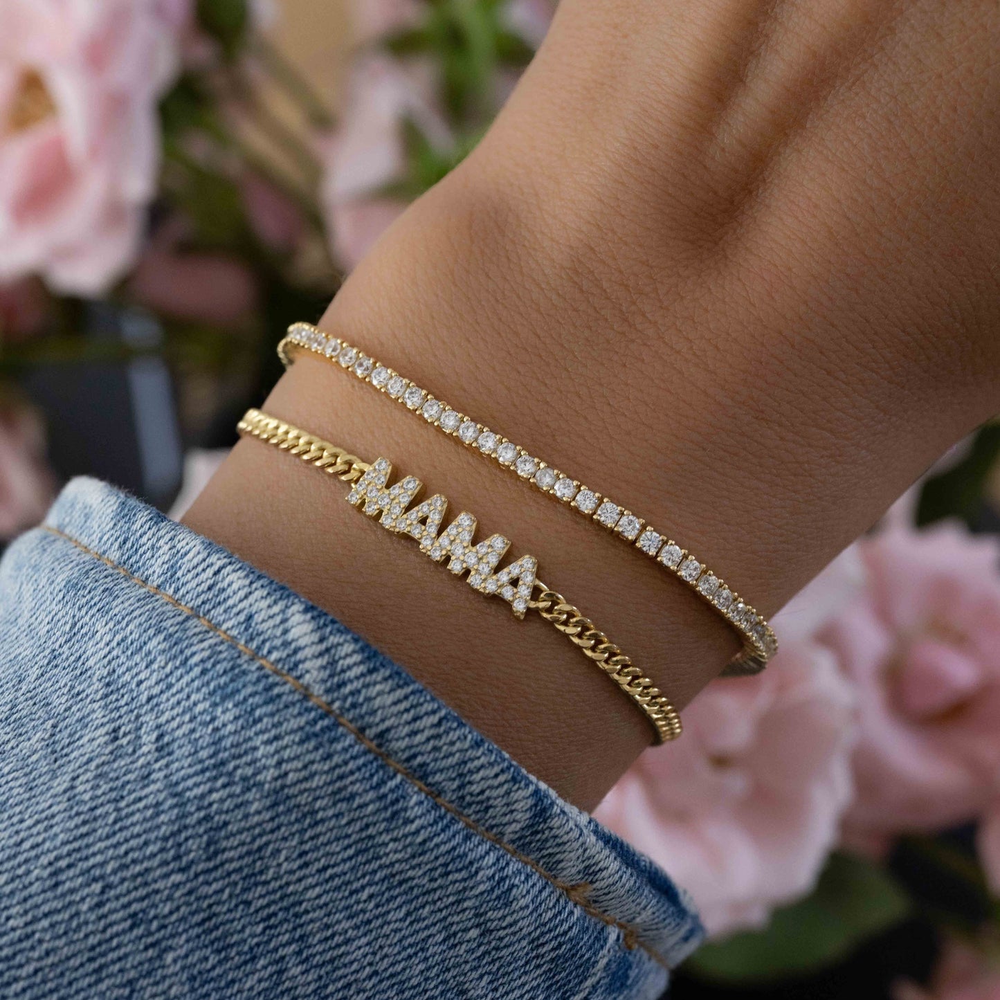 Model wearing bracelet stack featuring gold tennis bracelet paired with gold MAMA charm bracelet
