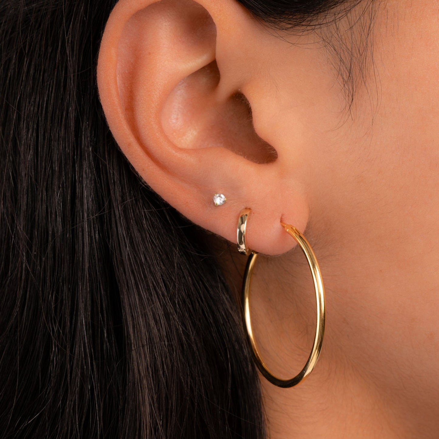 Model wearing gold earring stack featuring gold endless hoop earrings