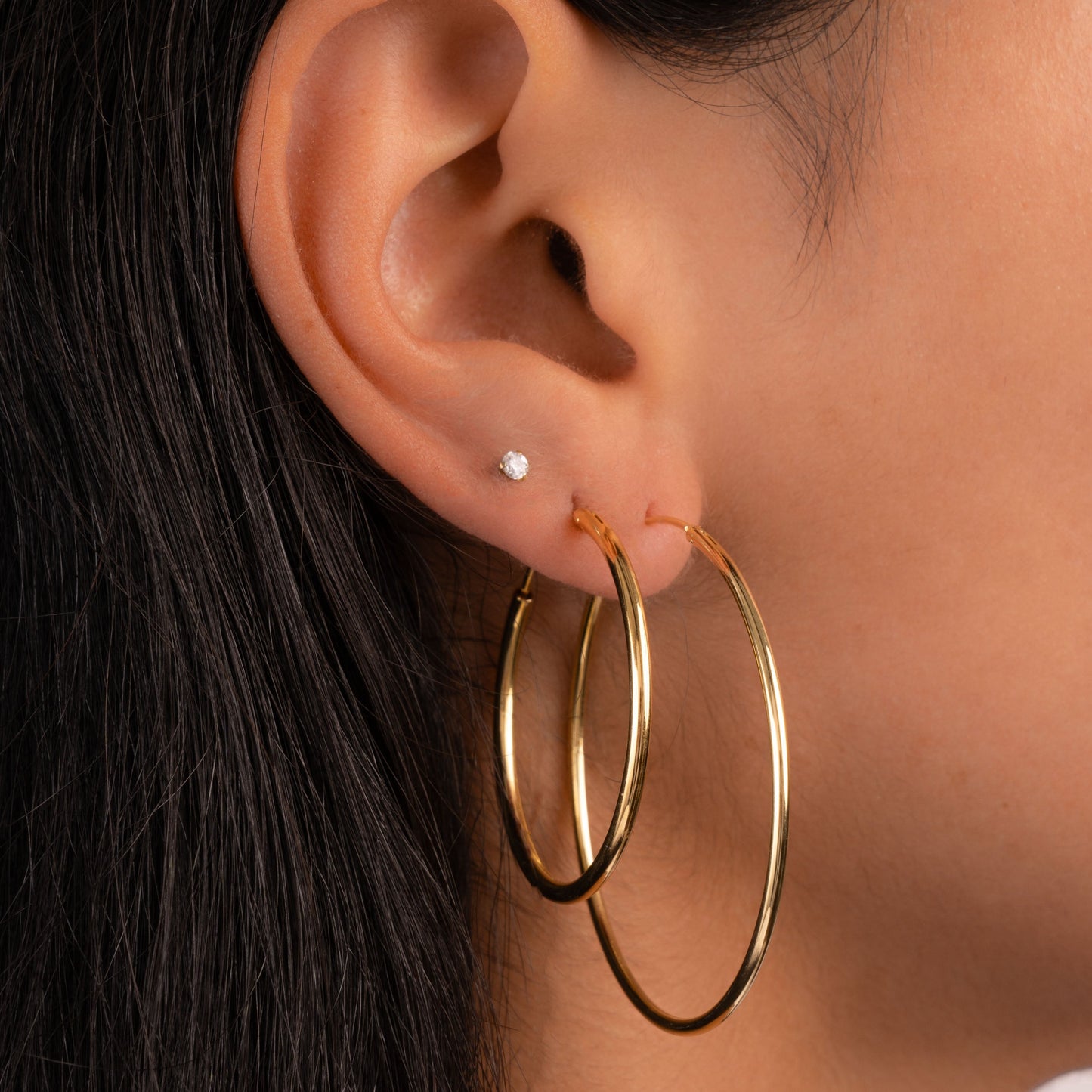 Model wearing gold skinny hoop earrings