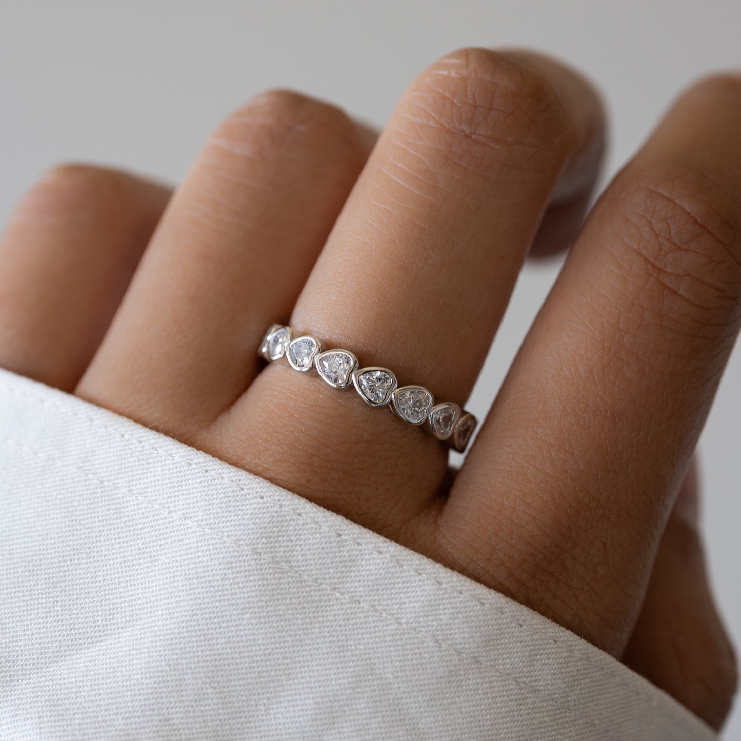 model wearing a sterling silver dainty heart eternity ring