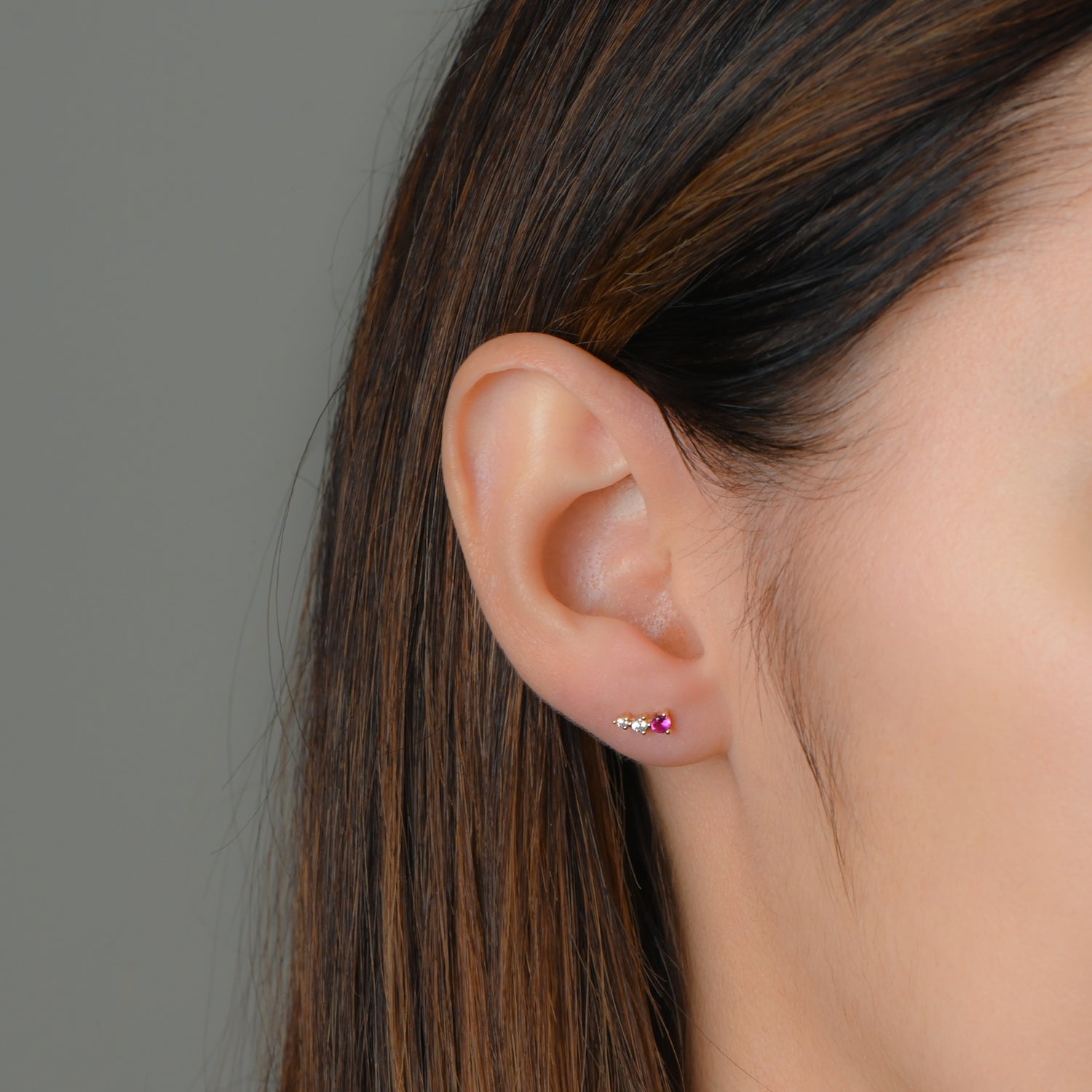 Model wearing gold ear climber stud earrings with ruby and diamonds.