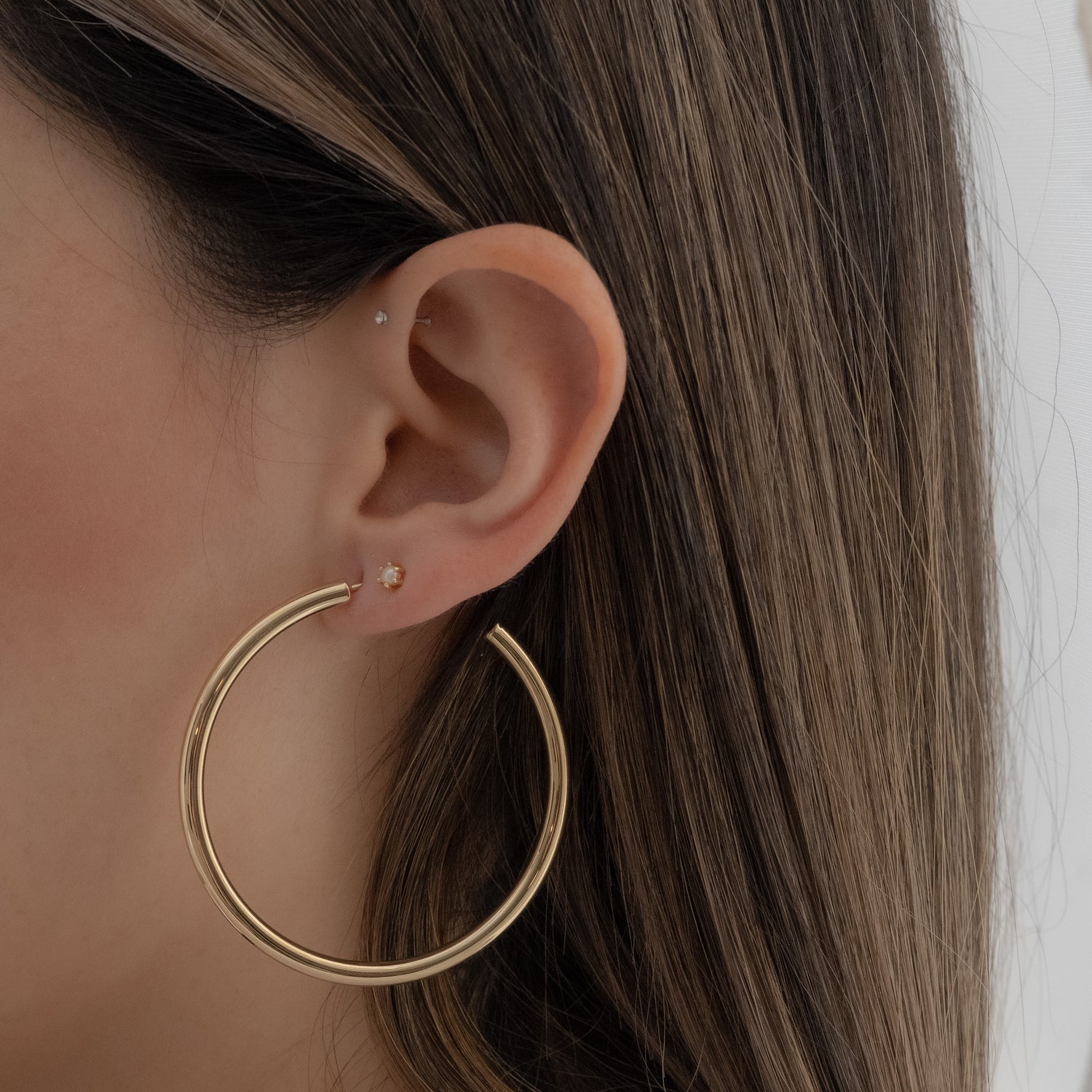Model wearing oversized classic gold Madison Beer inspired hoop earrings with a tiny pearl stud.