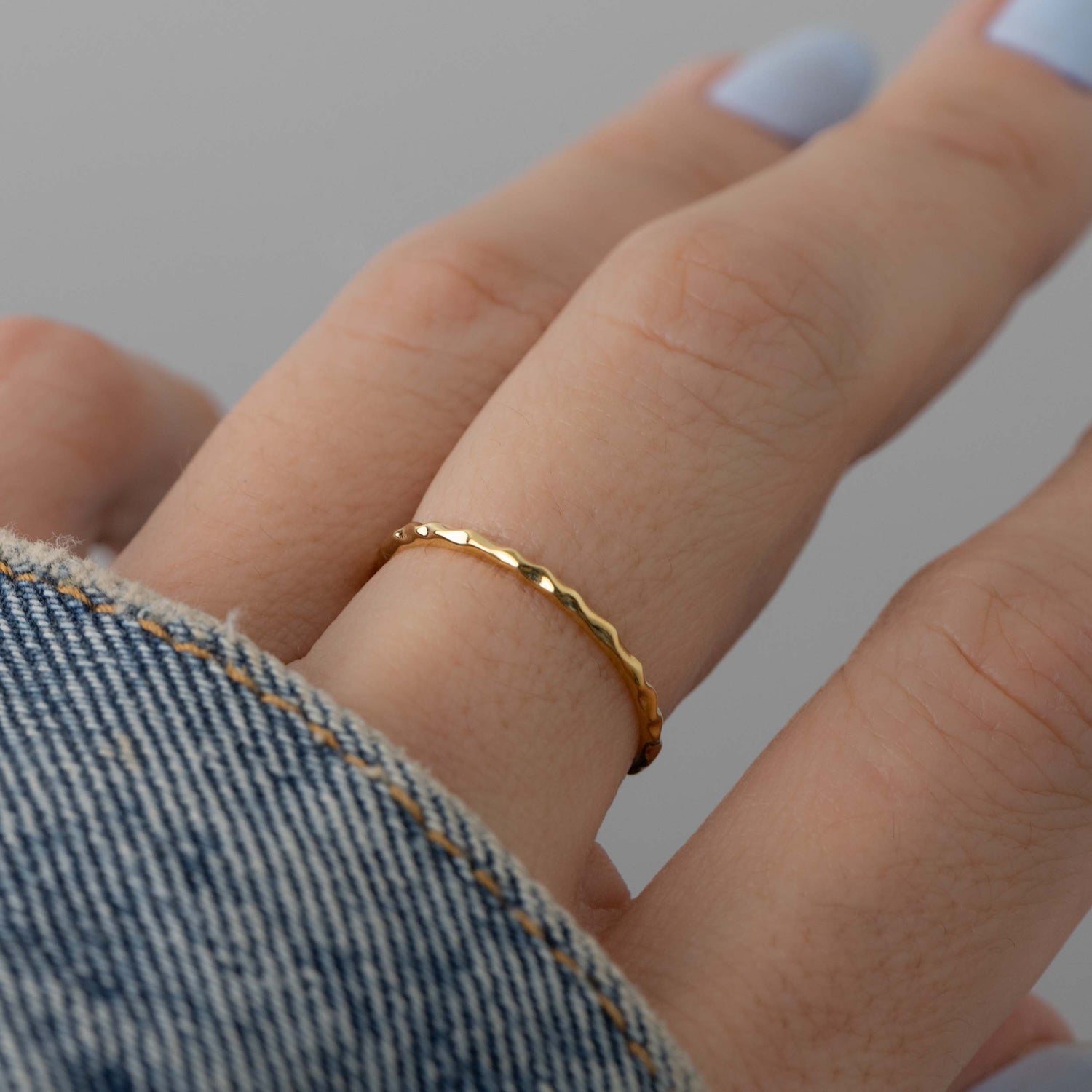 Model wearing dainty gold textured ring.