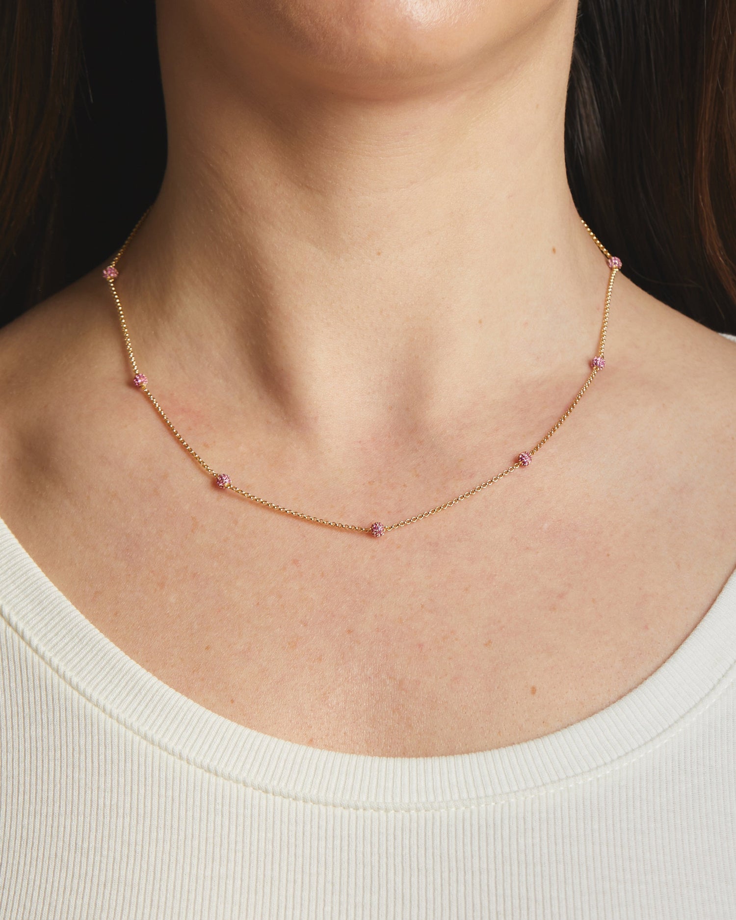 Model wearing dainty ruby pavé beaded ball necklace.