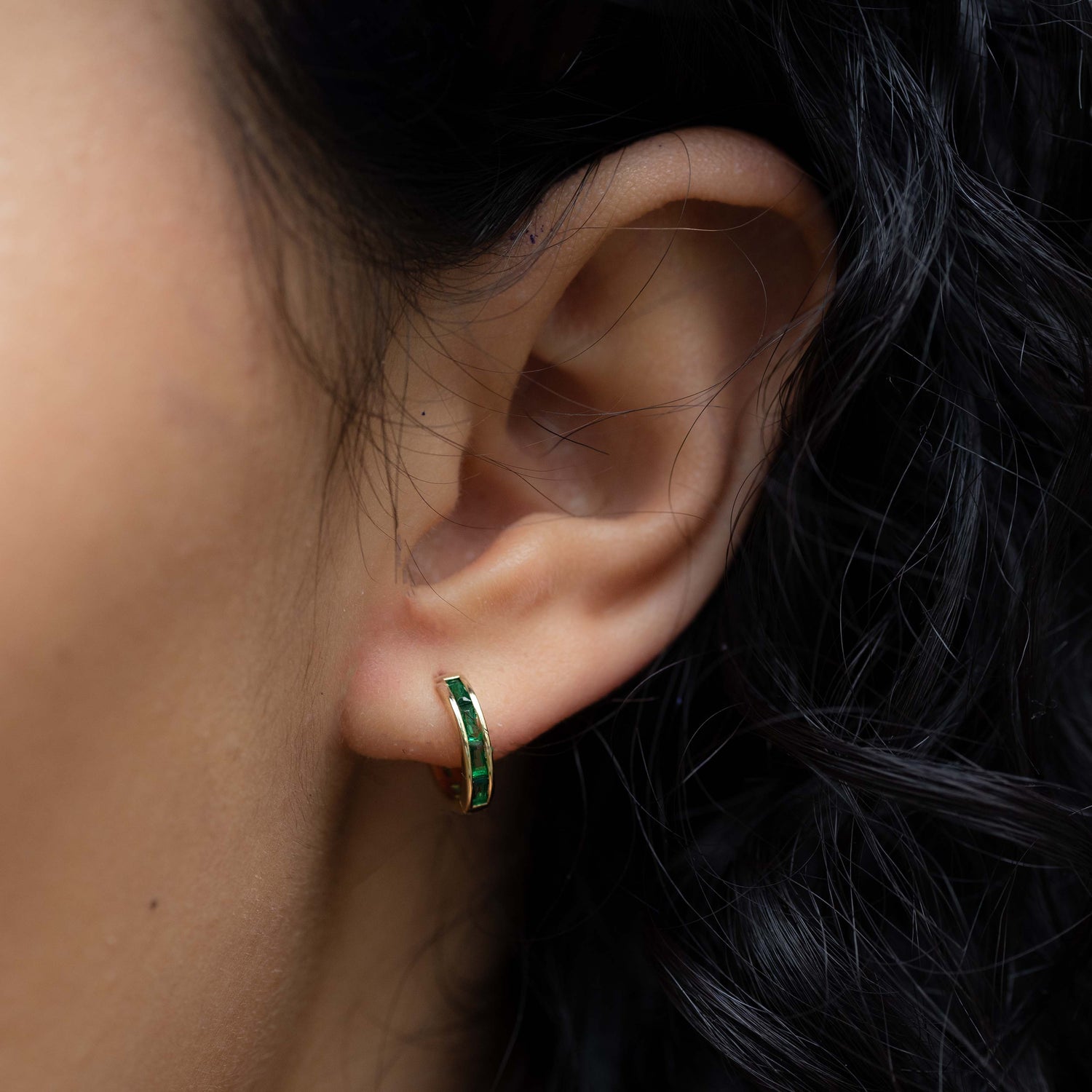 model wearing emerald huggie earring