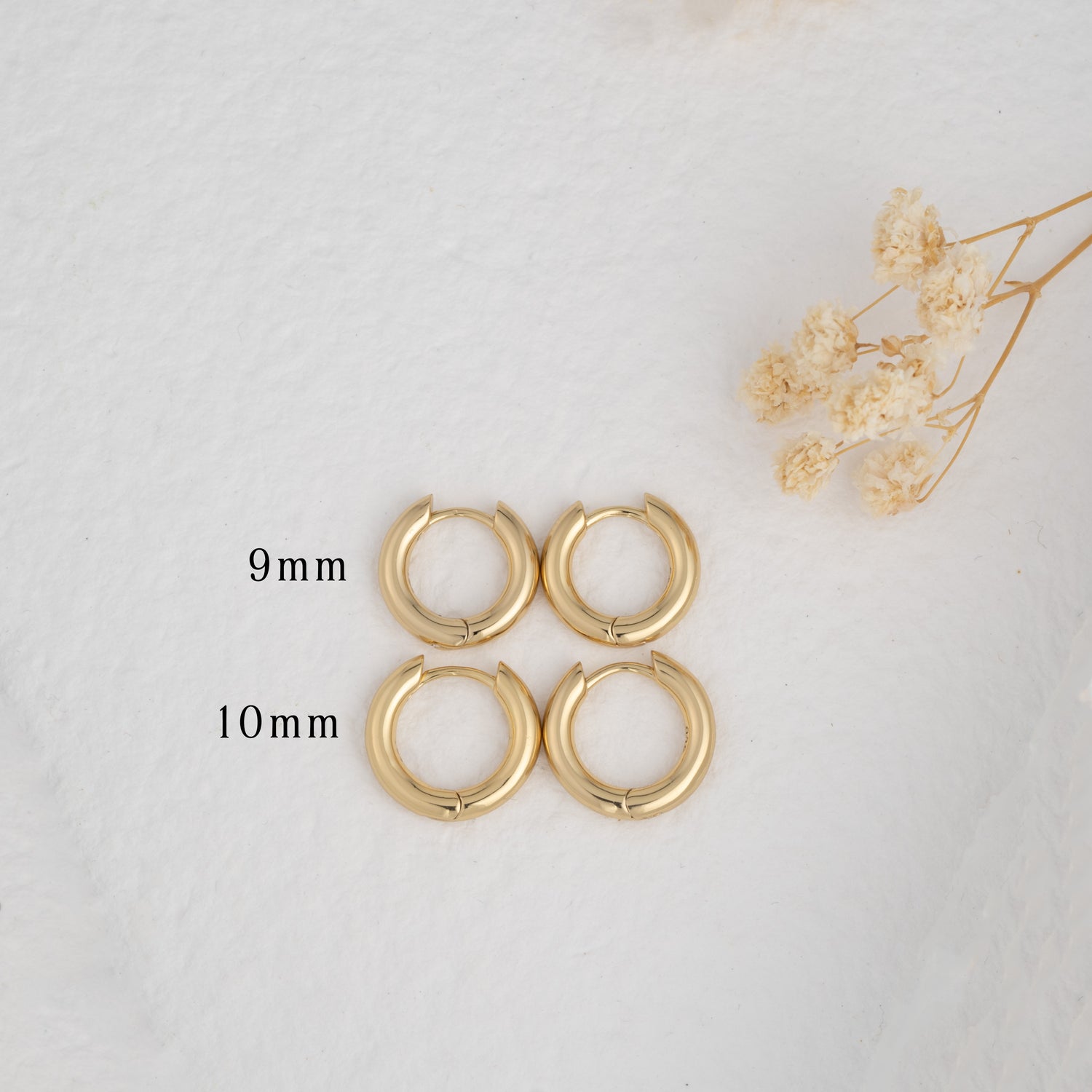 Gold hoop earrings on a plain background, one in 8mm and one in 10mm
