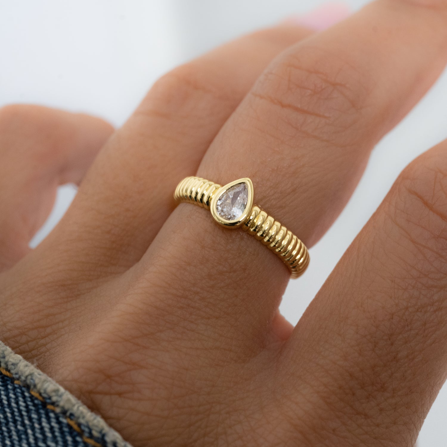 Model wearing Gold pear diamond ring with fluted band.
