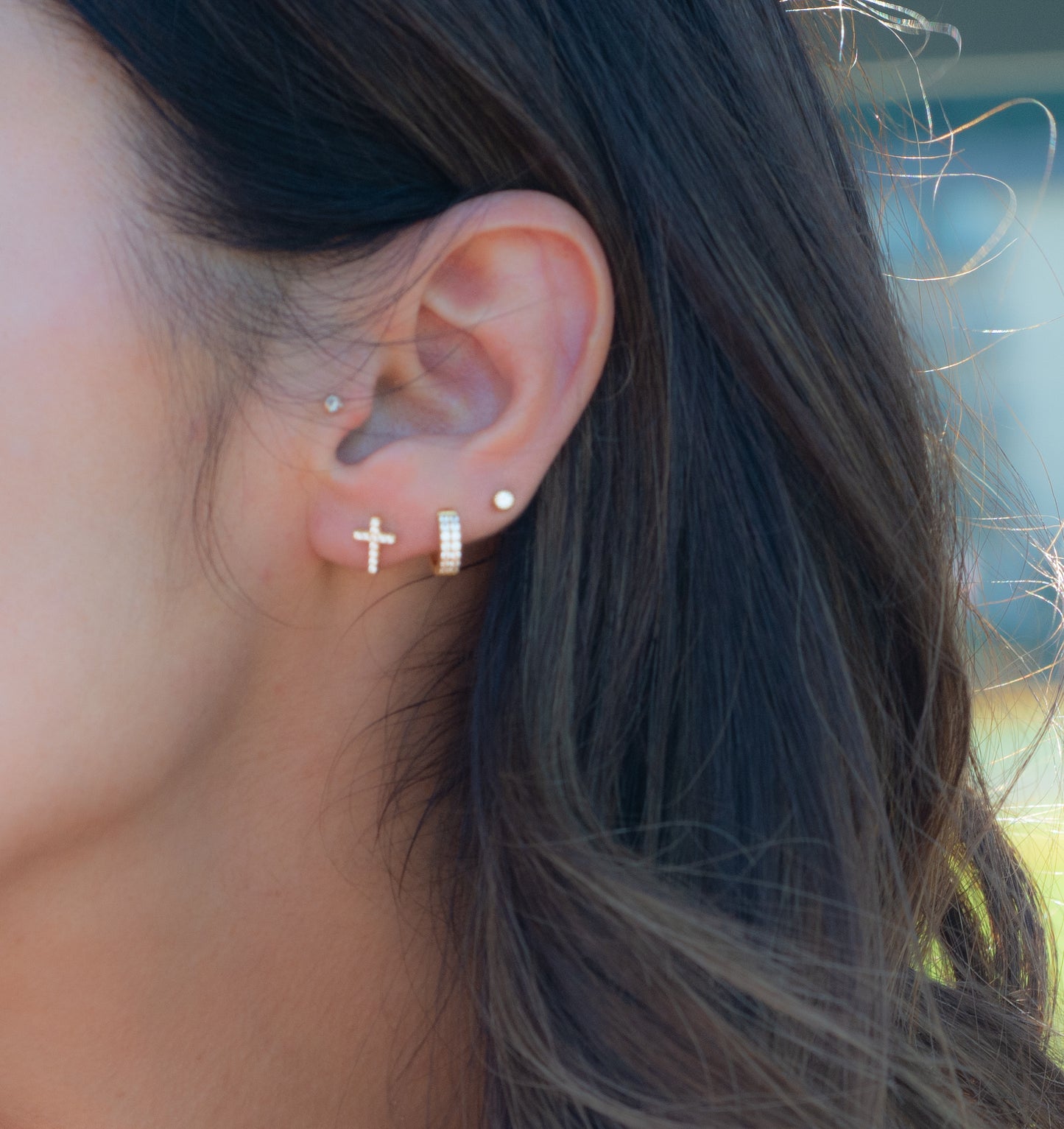 stud earrings layered with huggies and gold studs on model