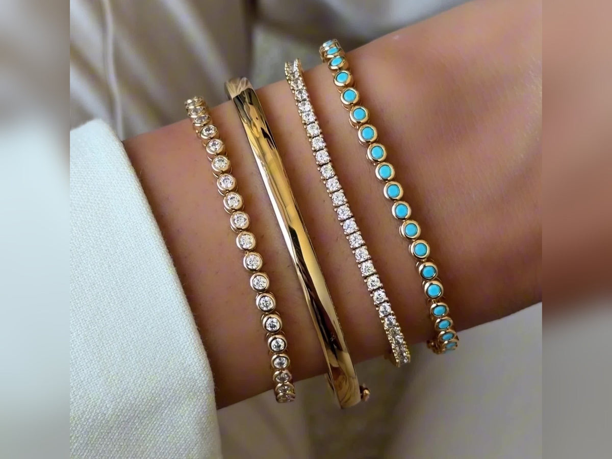 Turquoise, gold and clear-stone bracelets stacked on a wrist.