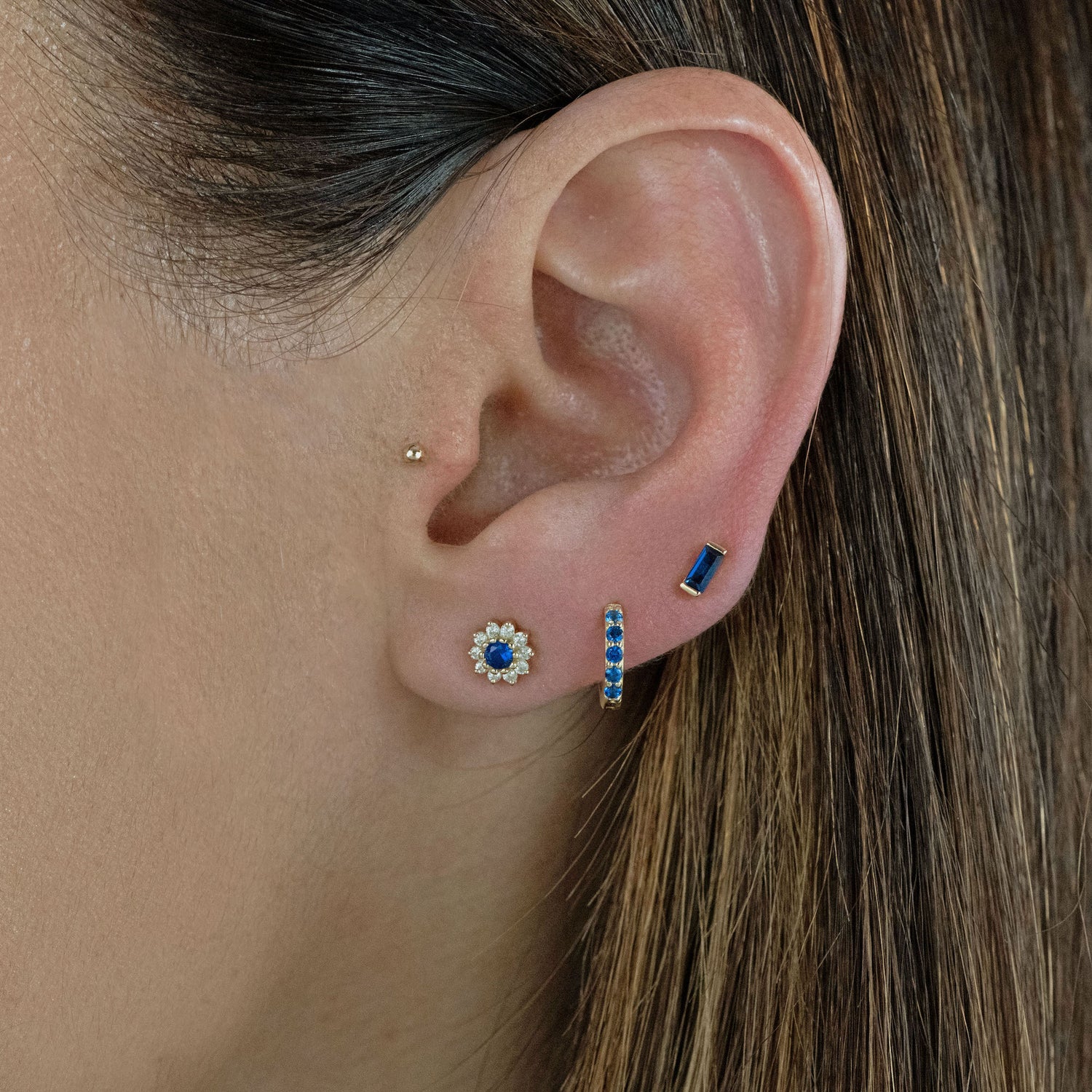 Sapphire gold earrings in a models ear.