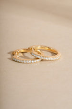 Close-up of 14K solid gold 11mm pavé lab-grown diamond huggie earrings by Sami Jewels on a flat lay.