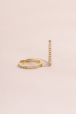 14K solid gold pavé lab-grown diamond huggie earrings with 11mm size, displayed on a pink background.