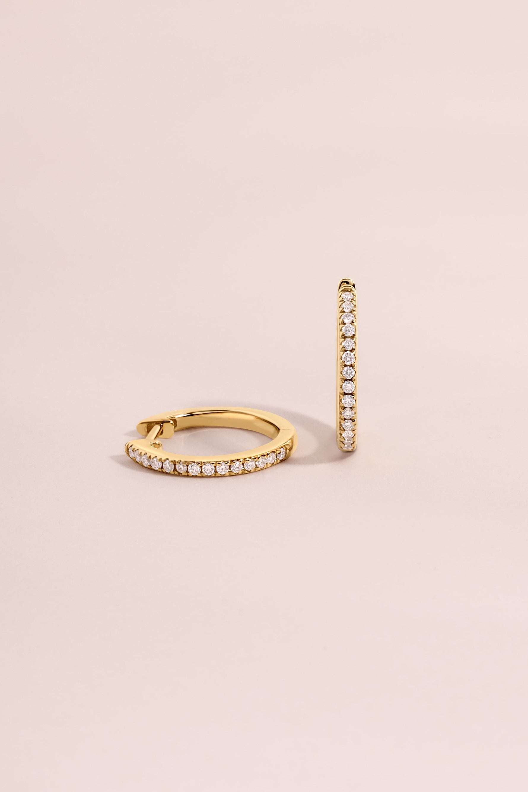 14K solid gold pavé lab-grown diamond huggie earrings with 11mm size, displayed on a pink background.