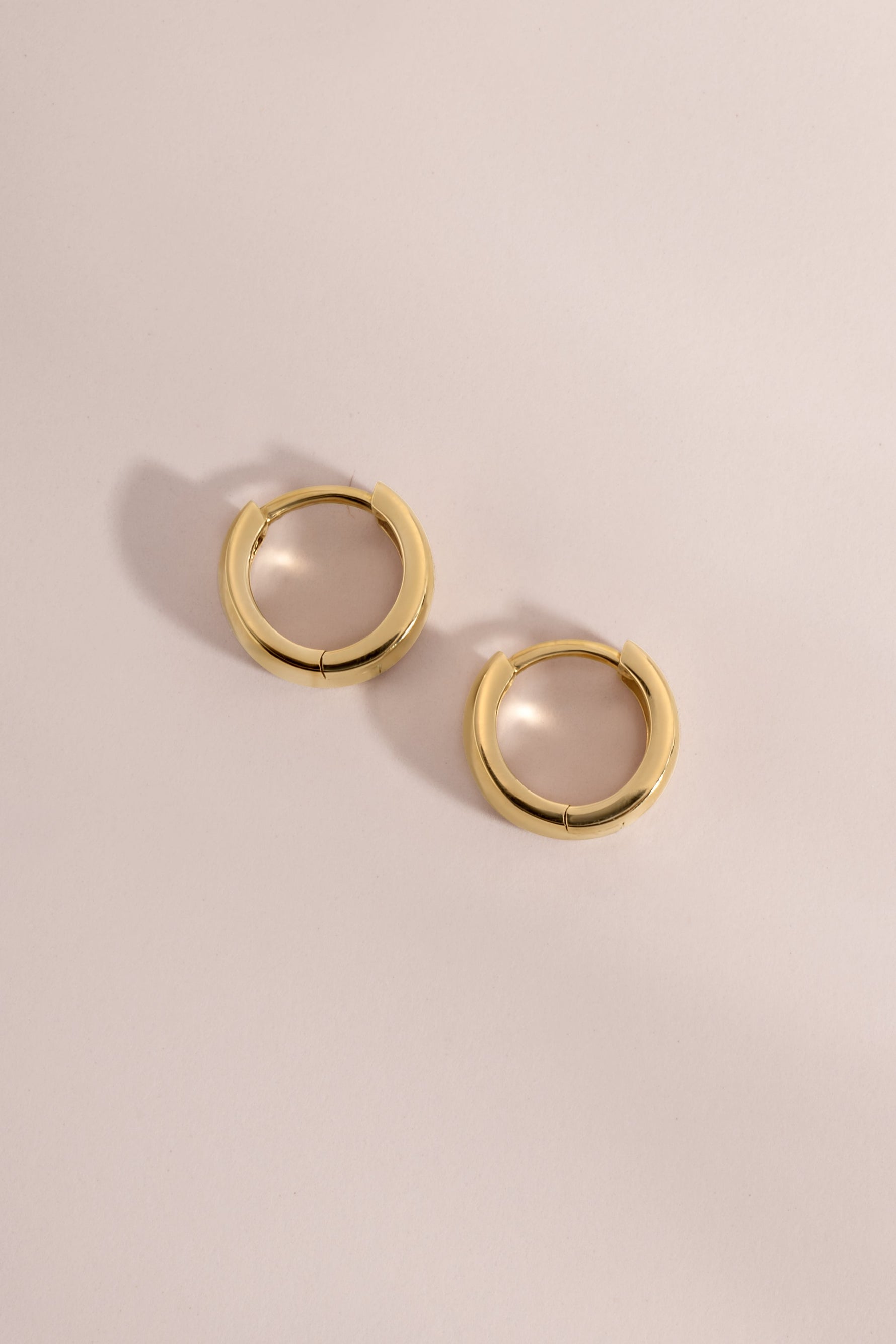 Side view of 14K solid gold chunky hoop earrings on a neutral background