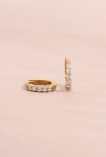 14K solid gold 7mm diamond huggie earrings side view on light pink background
