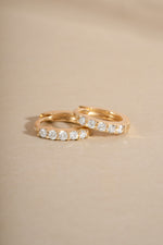 Pair of 14K solid gold 7mm diamond huggie earrings side view on neutral background