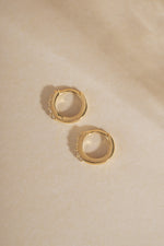 Pair of 14K solid gold 7mm lab grown diamond huggie earrings flat lay