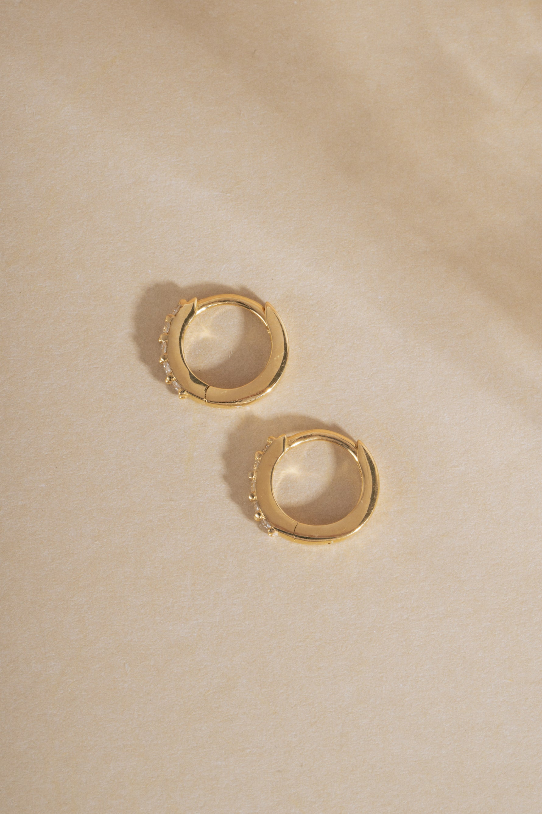 Pair of 14K solid gold 7mm lab grown diamond huggie earrings flat lay