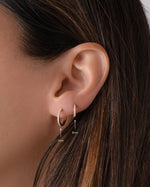 Close-up of an ear wearing 14K solid gold small hoop diamond earrings with size indicators.