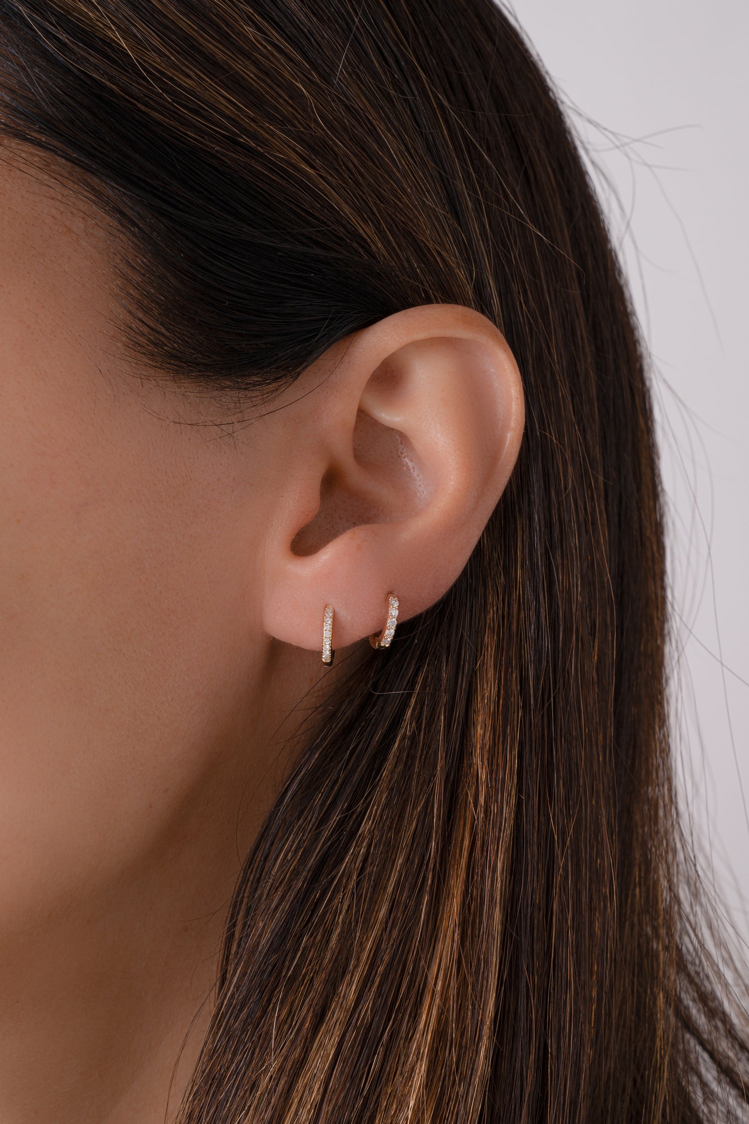 14K solid gold 8mm pavé diamond huggie earrings styled on ear with 7mm diamond huggies