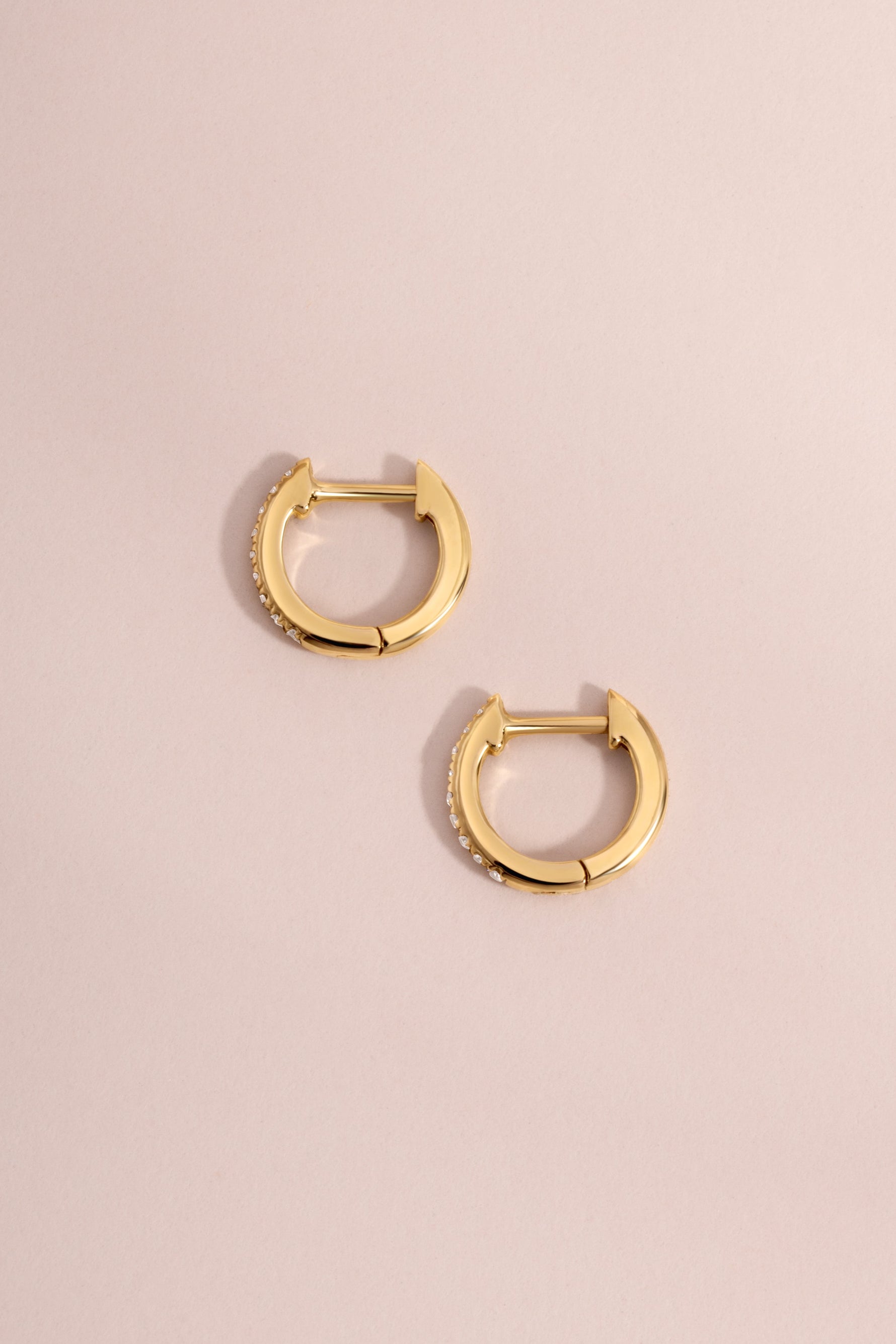 Pair of 14K solid gold 8mm pavé diamond huggie hoop earrings flat lay