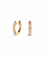 14K solid gold 8mm pavé diamond huggie earrings on white background