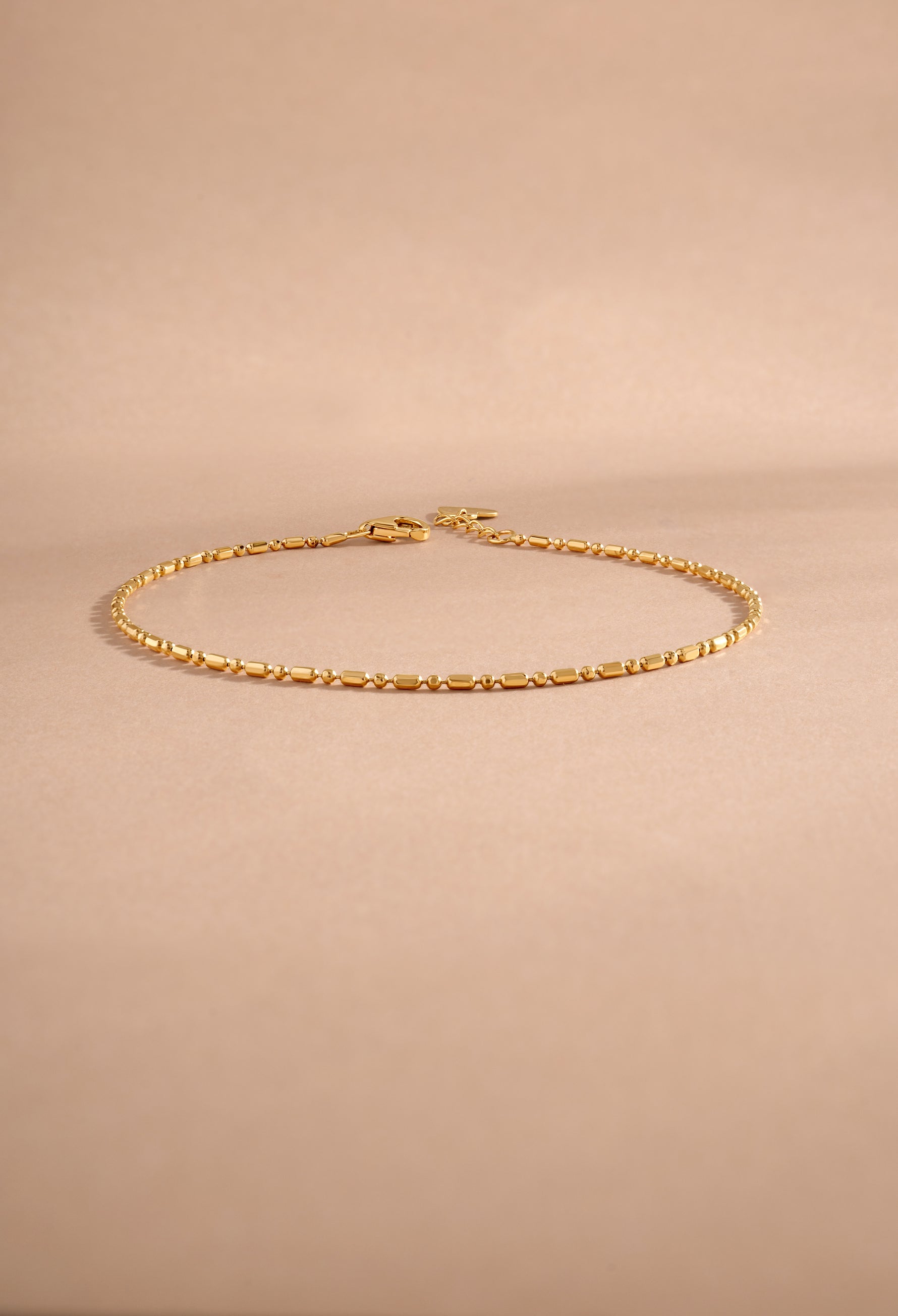 14K solid gold bar station chain bracelet styled flat lay on neutral background