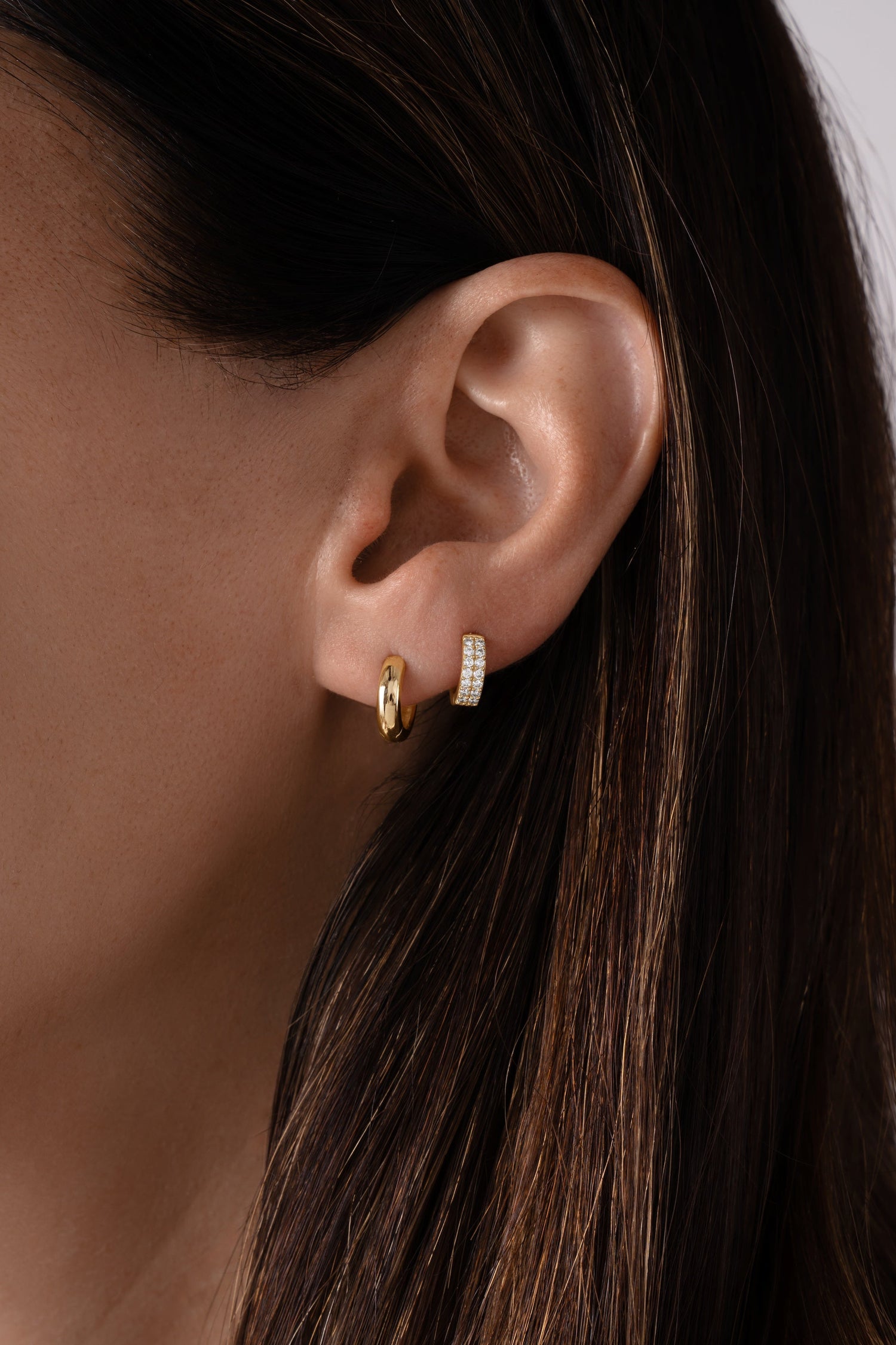 Solid 14K gold chunky huggie earrings styled with lab grown diamond huggies on model