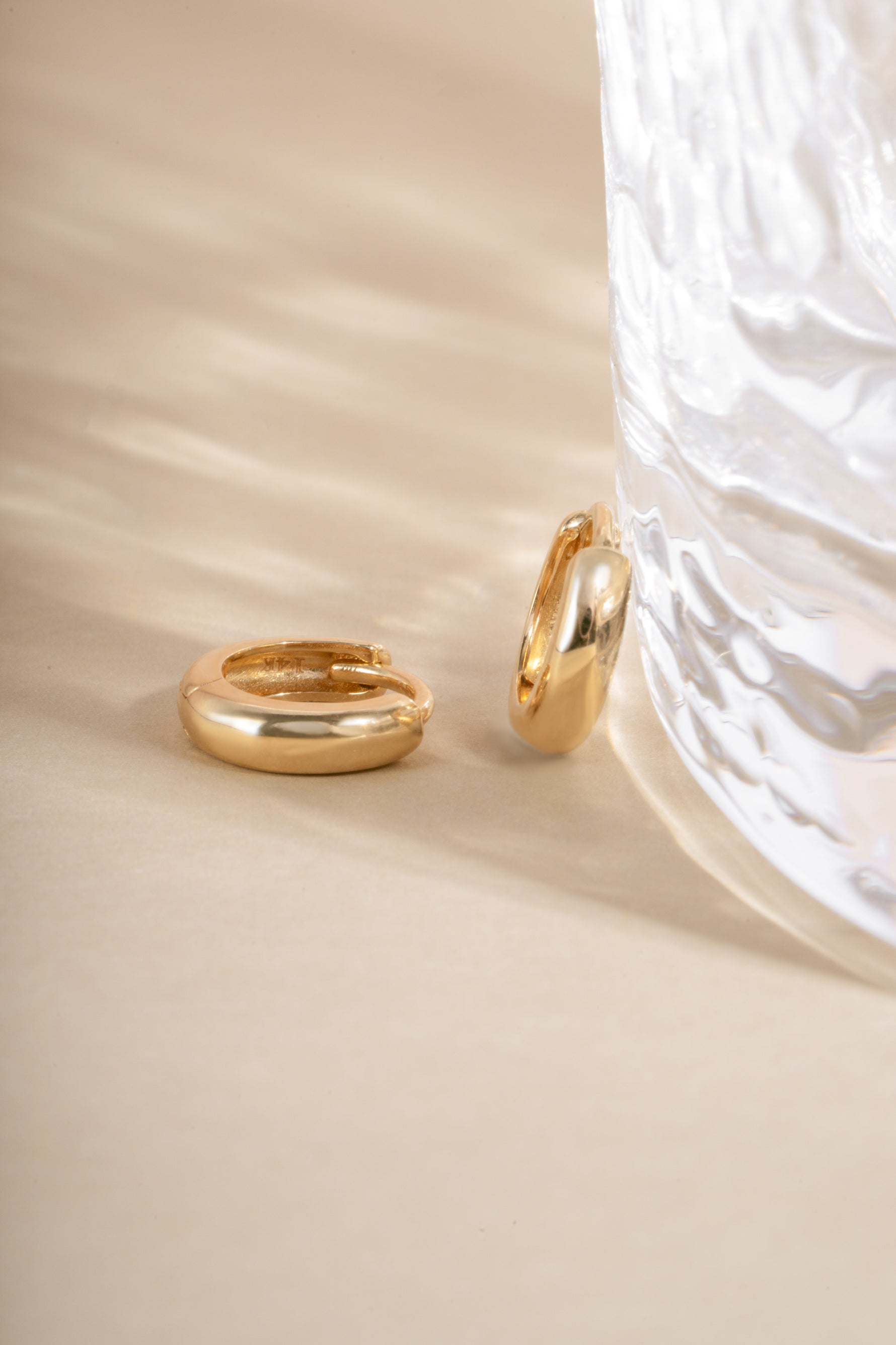 14K solid gold chunky huggie hoop earrings by Sami Jewels, close-up view showing the bold, shiny gold design.