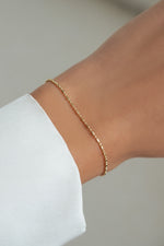 14K solid gold dainty chain bracelet worn on wrist against white background