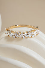 Close-up of 14K solid gold ring with brilliant marquise and round diamonds on a white object against neutral background