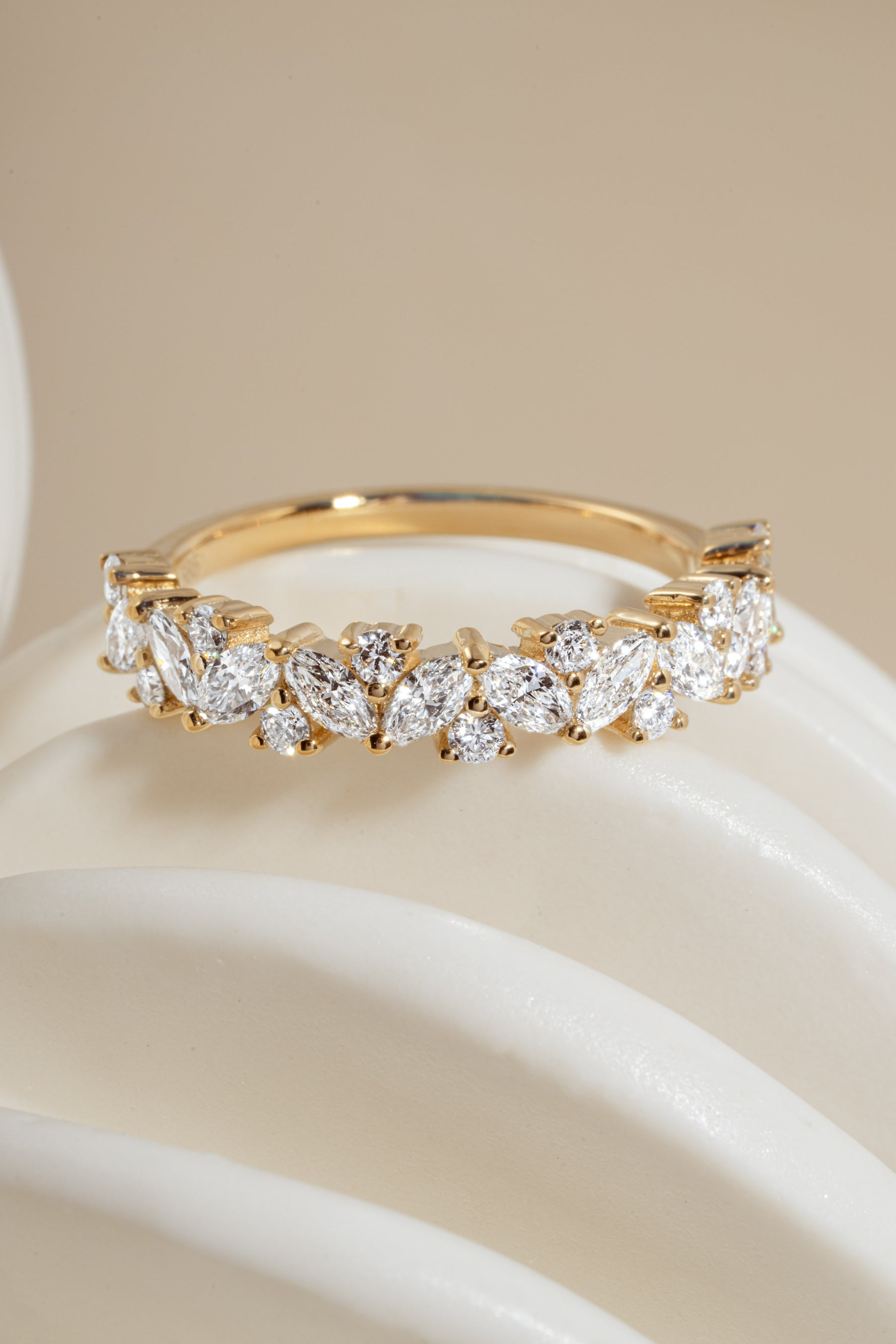Close-up of 14K solid gold ring with brilliant marquise and round diamonds on a white object against neutral background