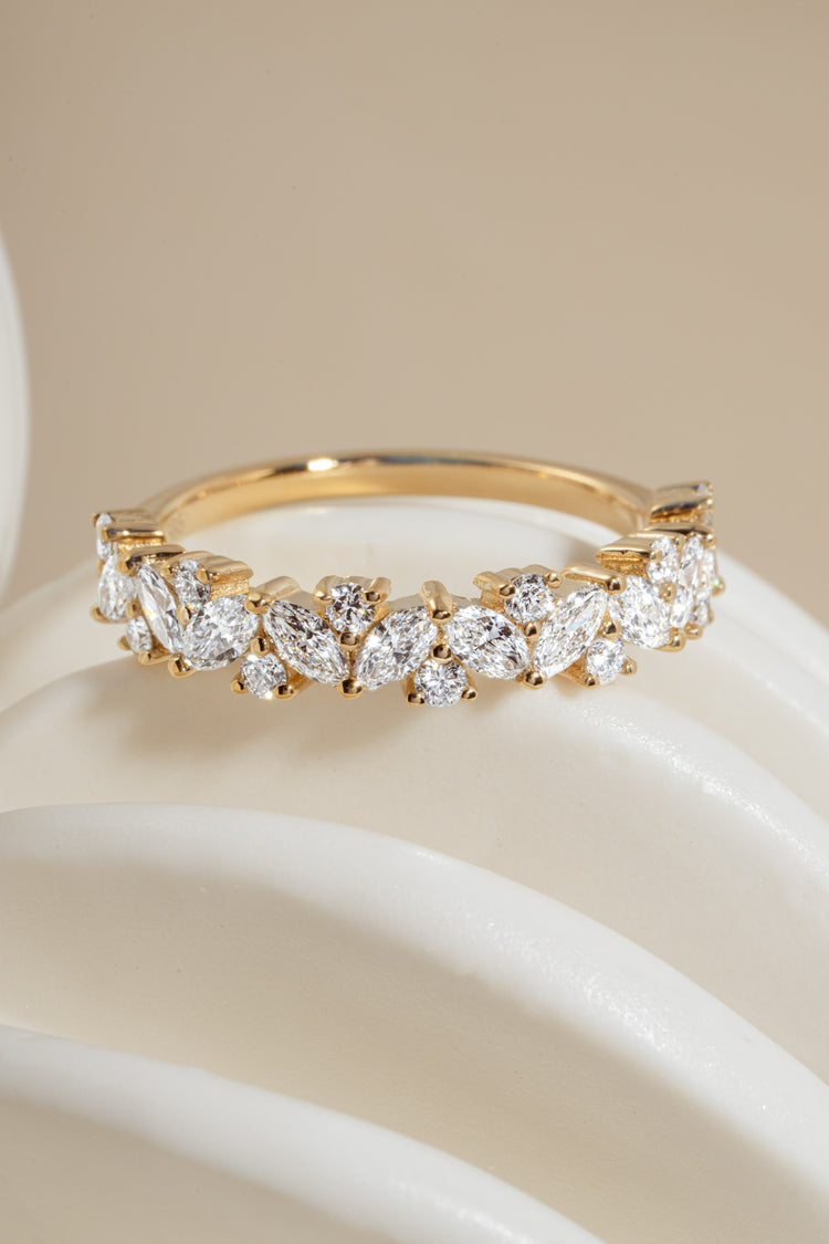 Close-up of 14K solid gold ring with brilliant marquise and round diamonds on a white object against neutral background