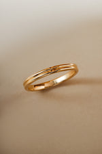 Solid gold double band wedding ring angled on a beige background