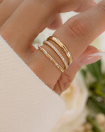 Close-up of hand wearing fine jewelry solid gold diamond rings with a blurred floral background