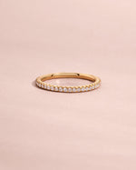 Solid gold diamond eternity ring with small pave stones on a light pink background