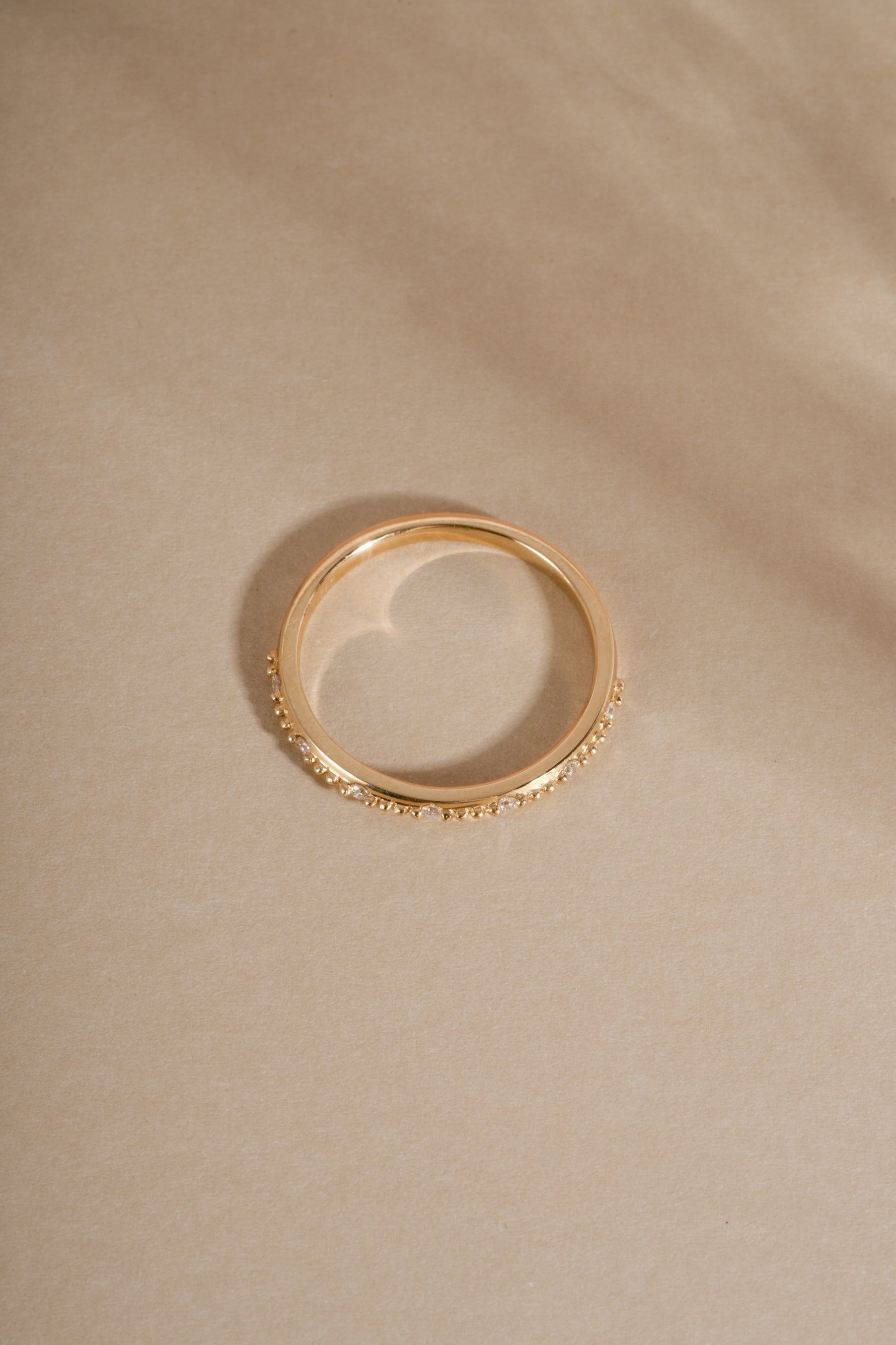 Angled view 14K solid gold wedding band with real diamonds on neutral background
