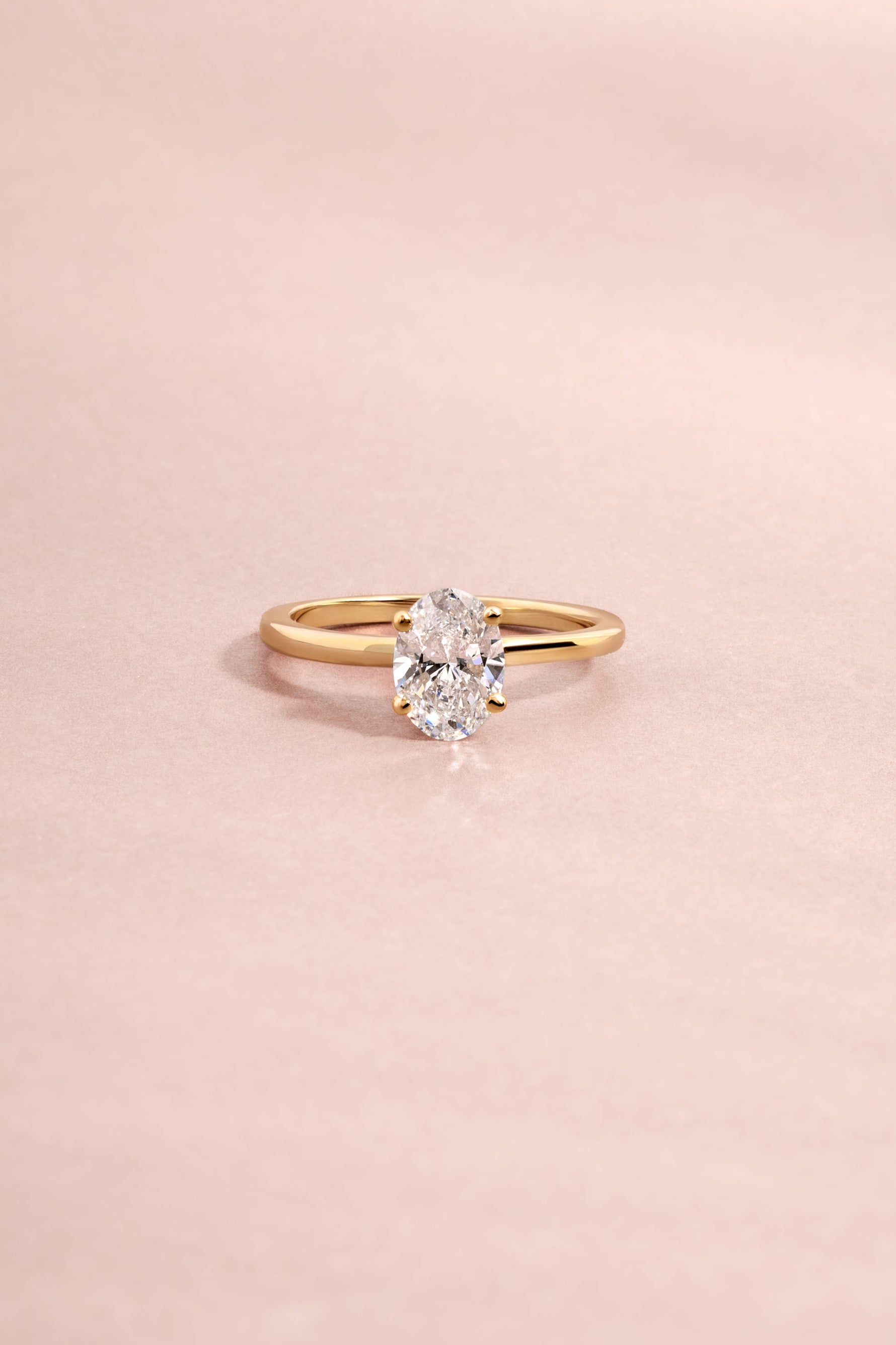 Solid 14k yellow gold oval solitaire lab diamond ring styled for fine jewelry on light pink background