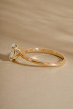 Side view of 14K solid gold oval cut engagement ring on neutral background